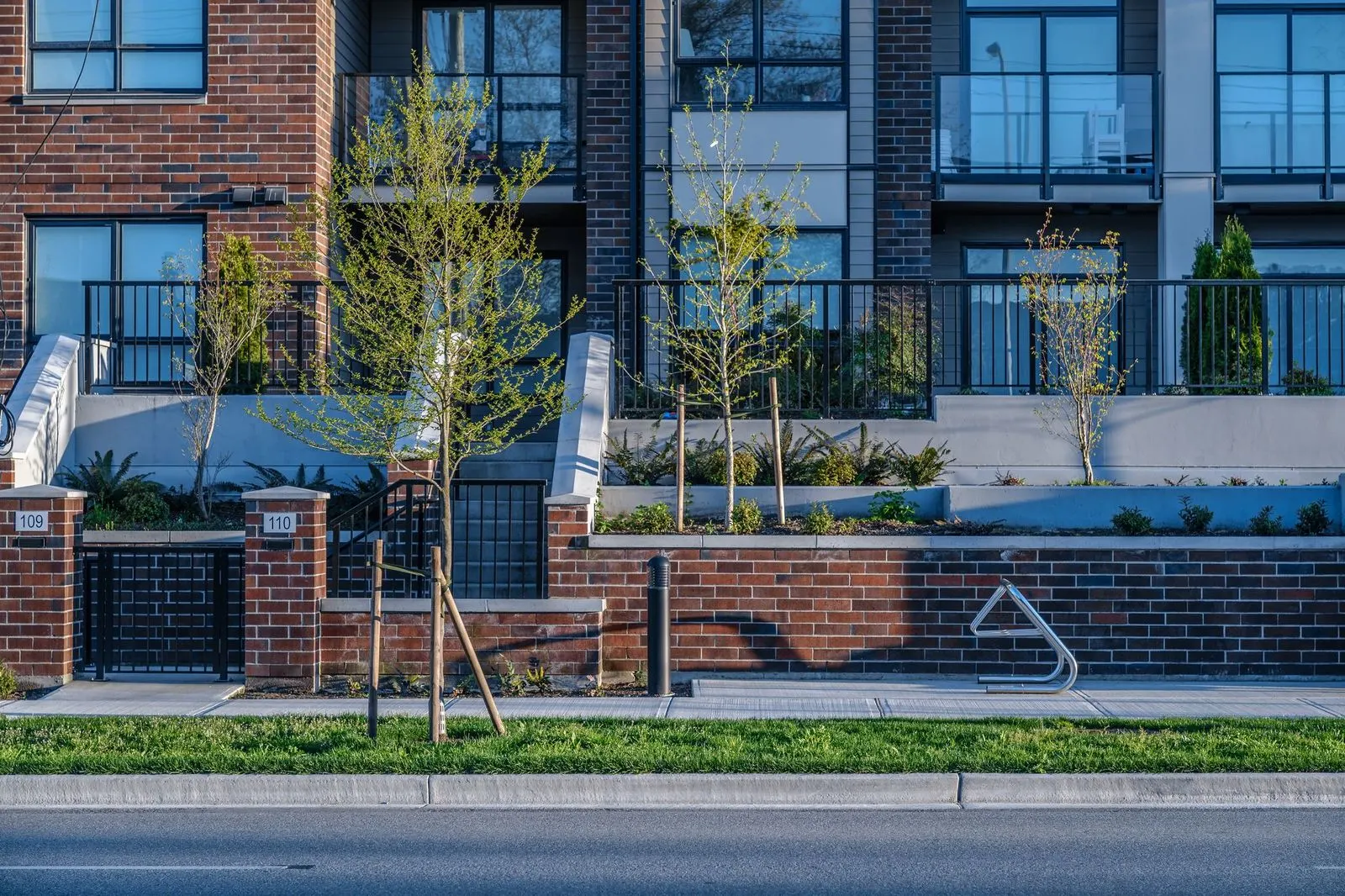 Raised brick planters and young trees along a street at Spark