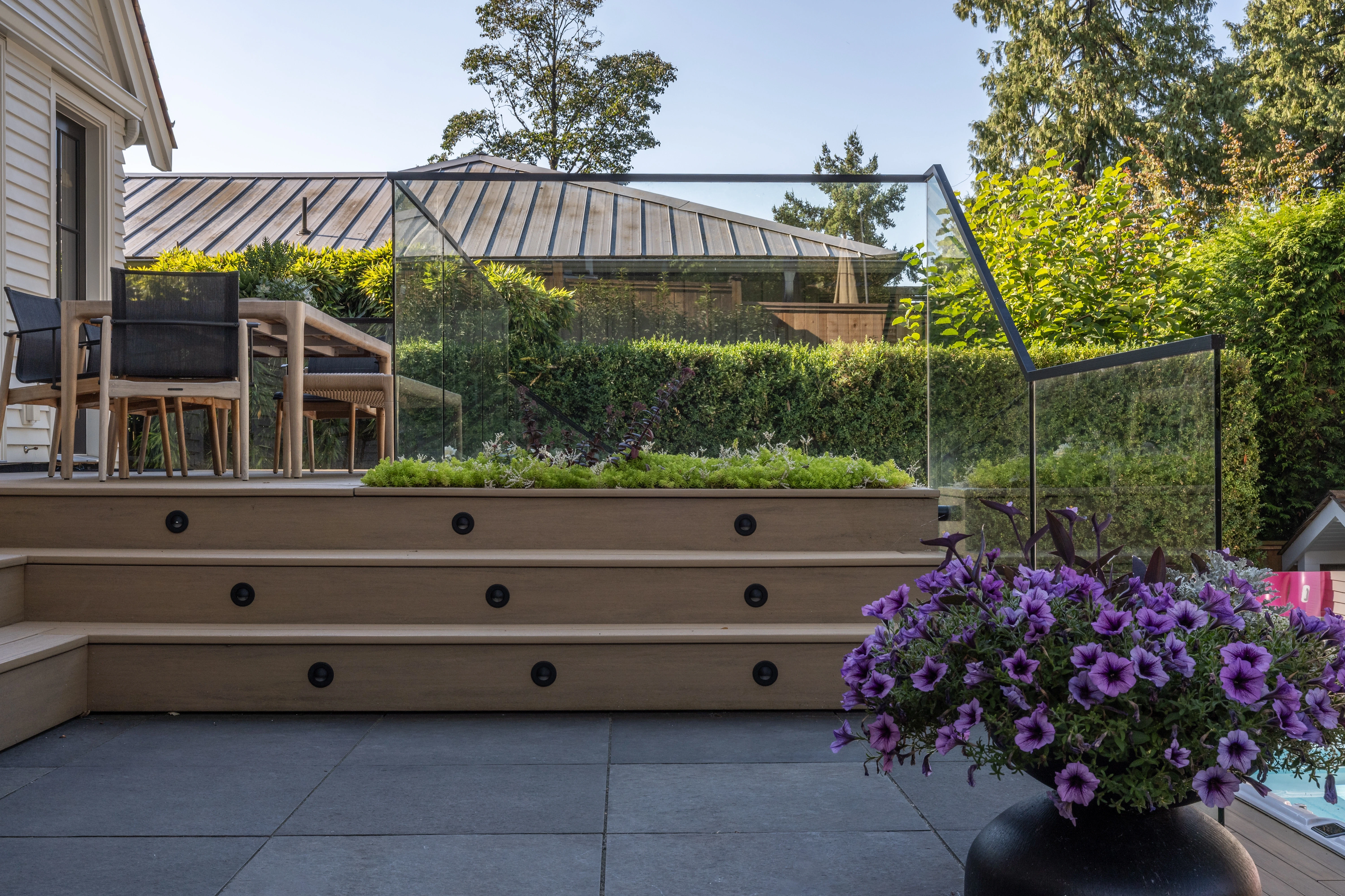 Terraced patio with flowering planters and glass railing at MacKenzie