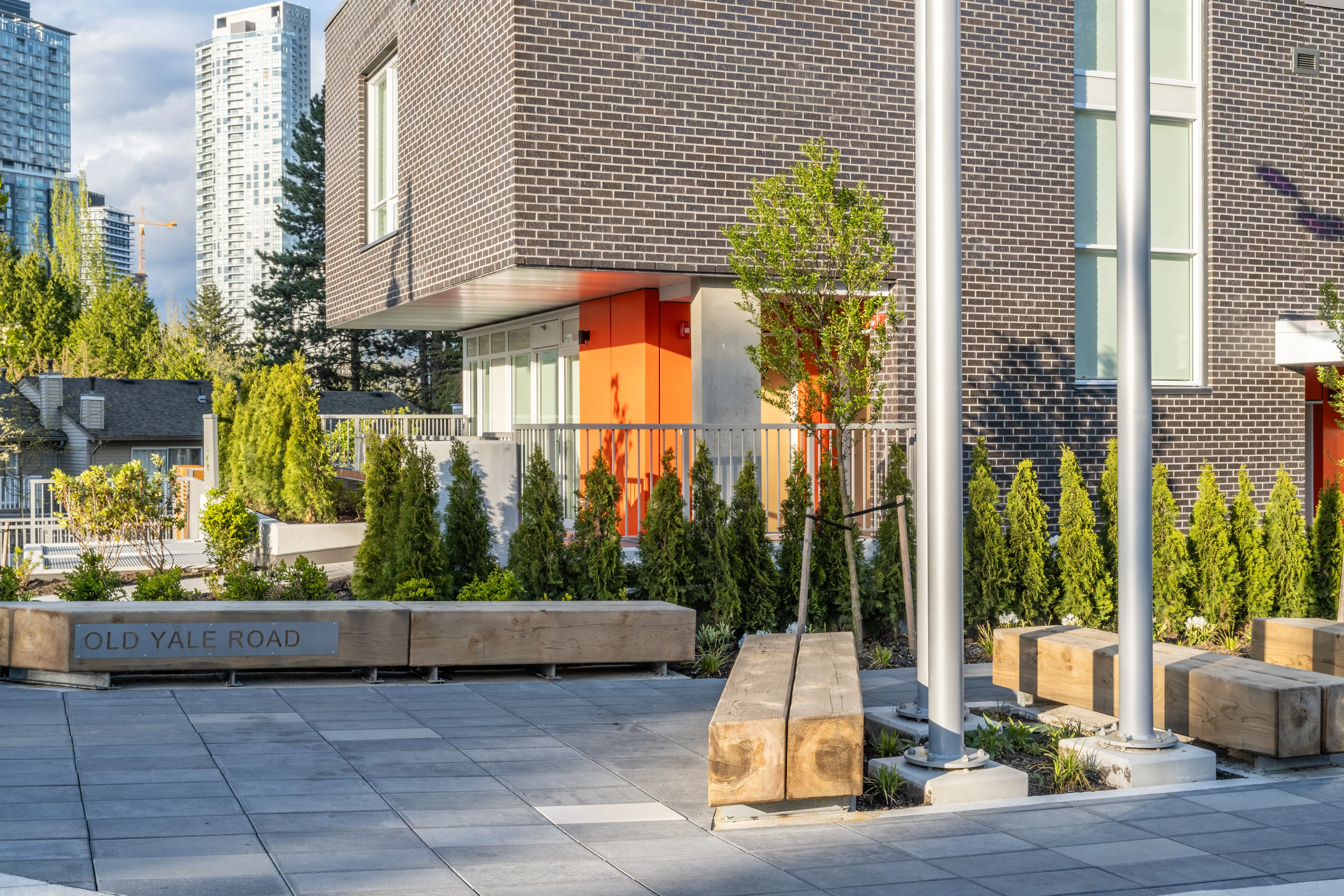 Paved plaza with timber benches and planting at The Holland II