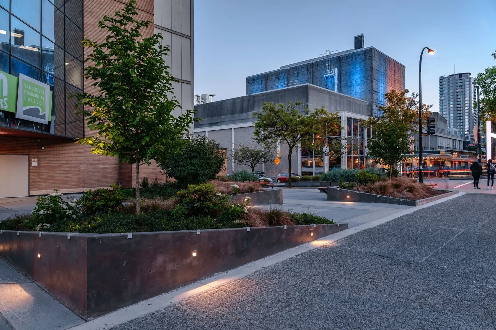 Planters with uplighting and trees on a plaza at dusk at Vancouver Community College