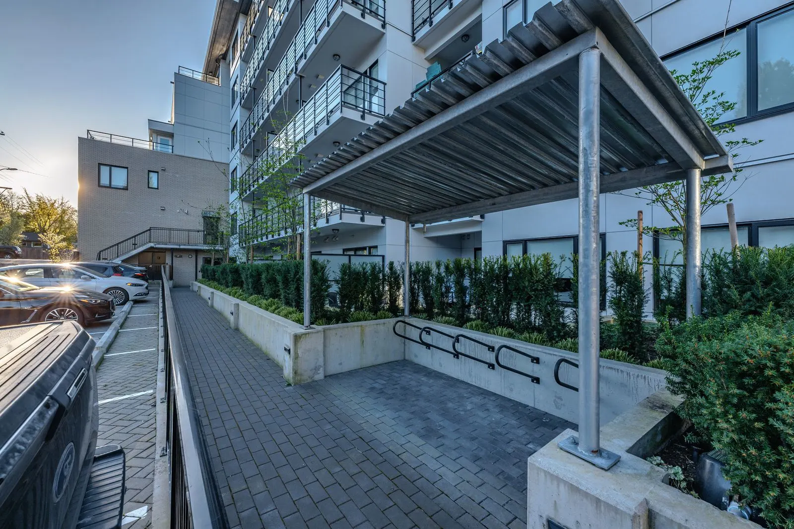 Covered entry walkway with hedges and bike racks at The Saint George