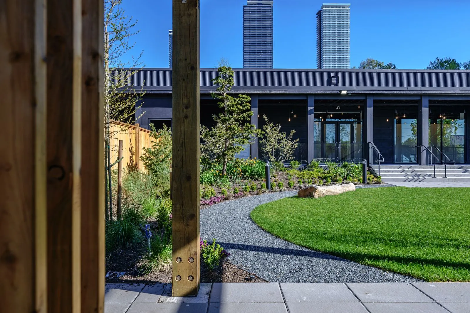 Lawn and gravel path viewed through timber posts at The Grove Presentation Centre