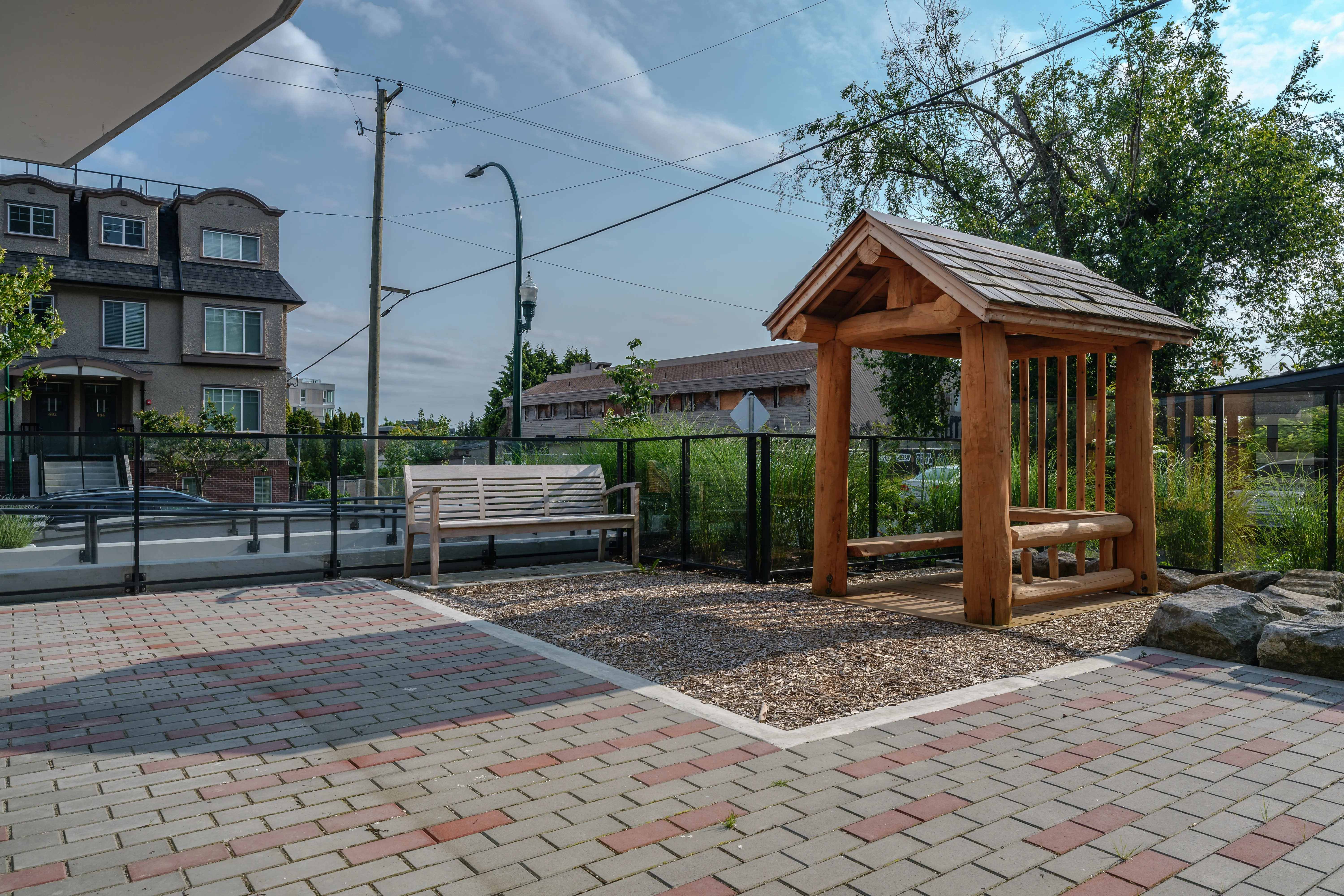 Timber gazebo on a paver plaza beside a fence at Parkhouse