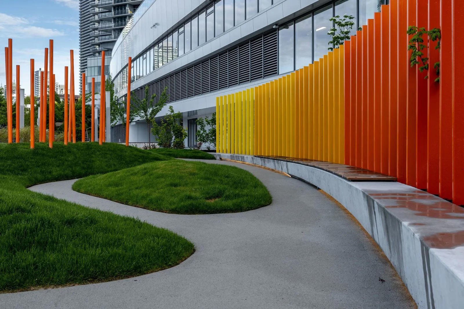 Curved path and grass mounds beside orange vertical fins at Brentwood 1B