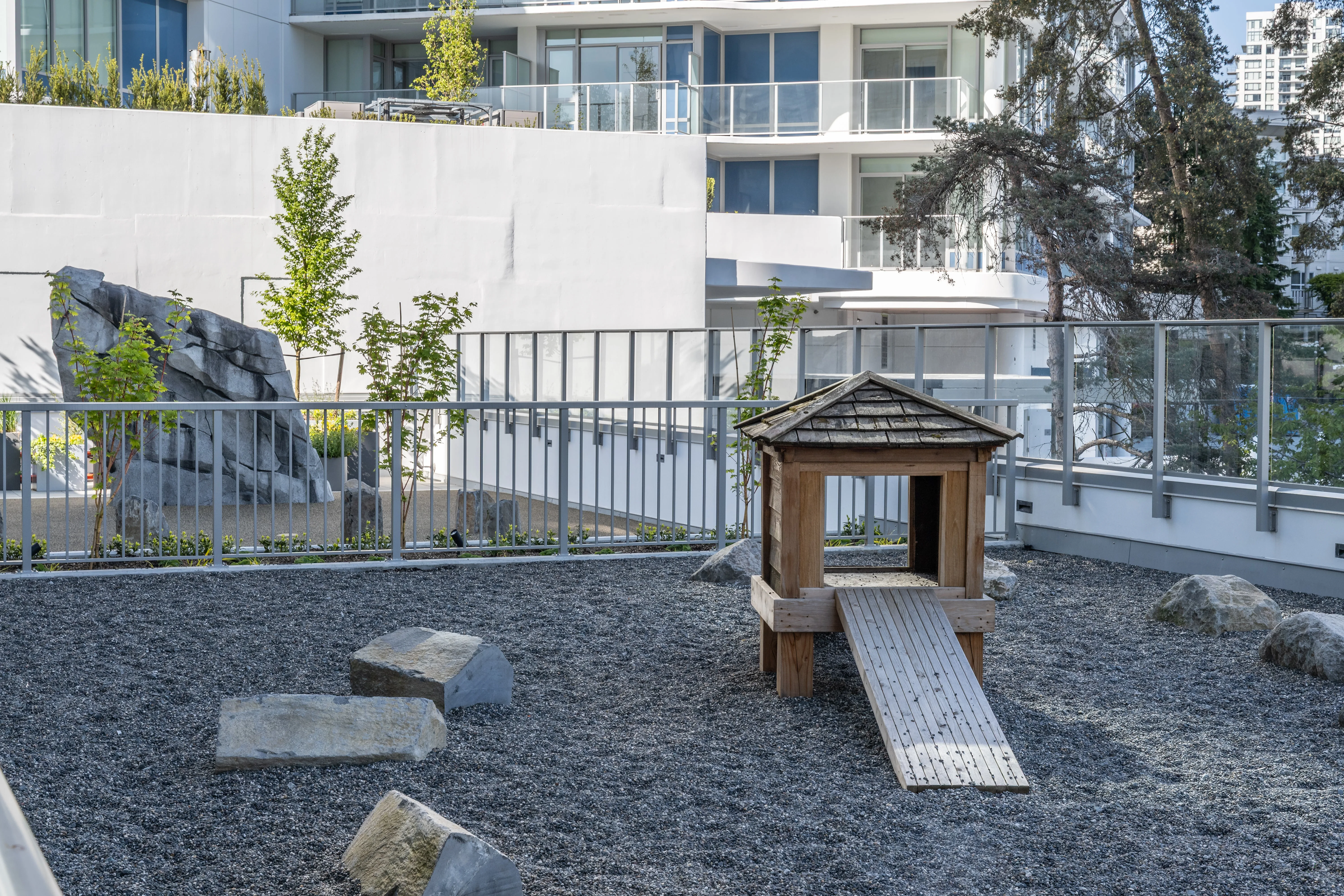 Small timber playhouse with slide on a gravel play area at Meridian