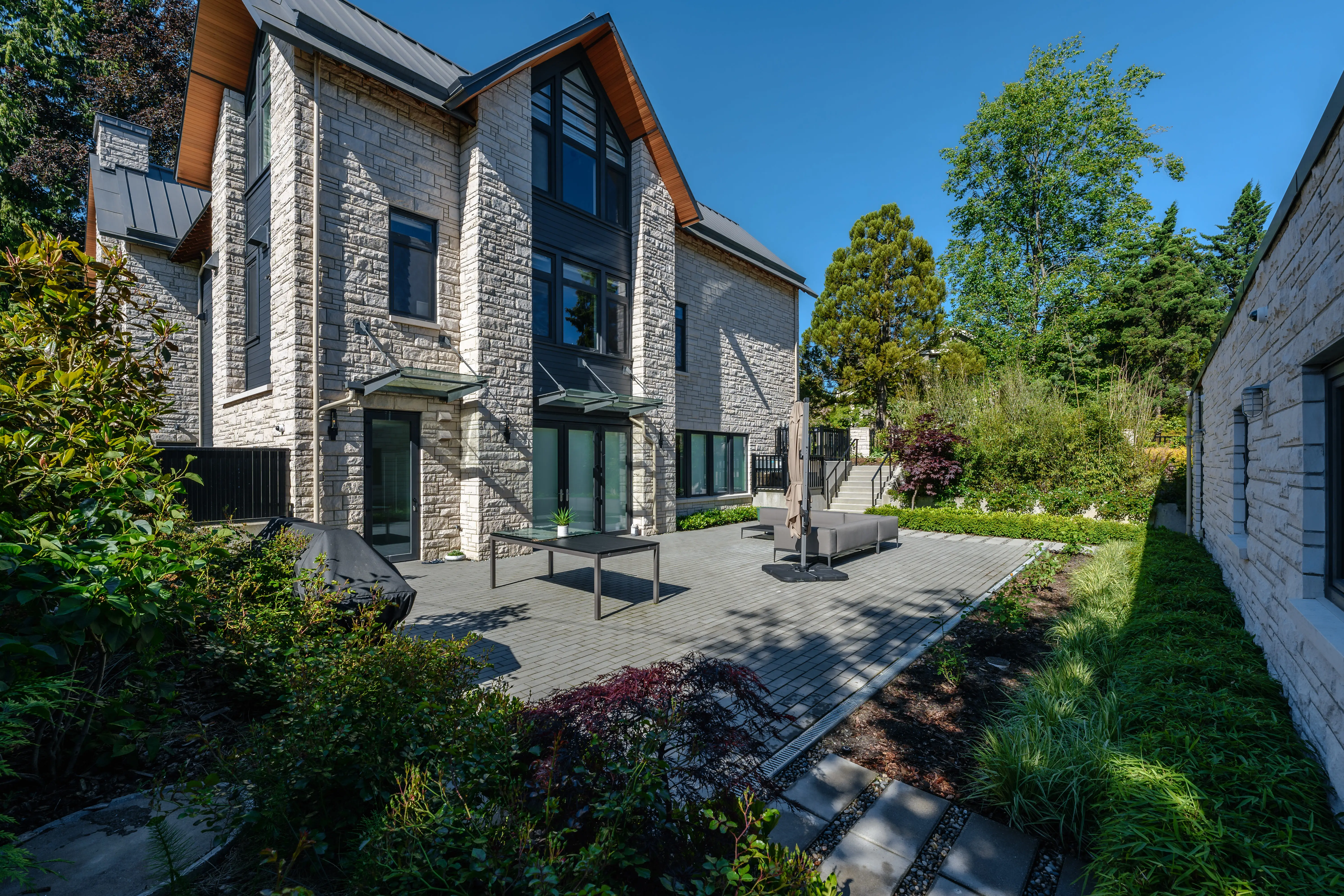 Paved courtyard with planting beside a stone-clad house at Hudson Street