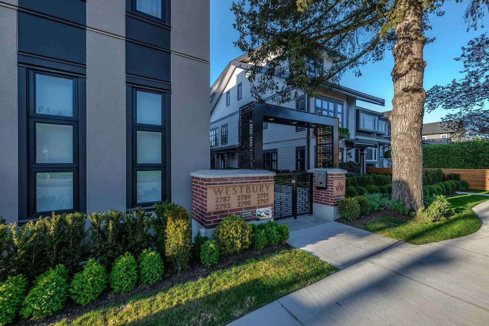 Shrub planting and sign along a walkway at Westbury Townhomes