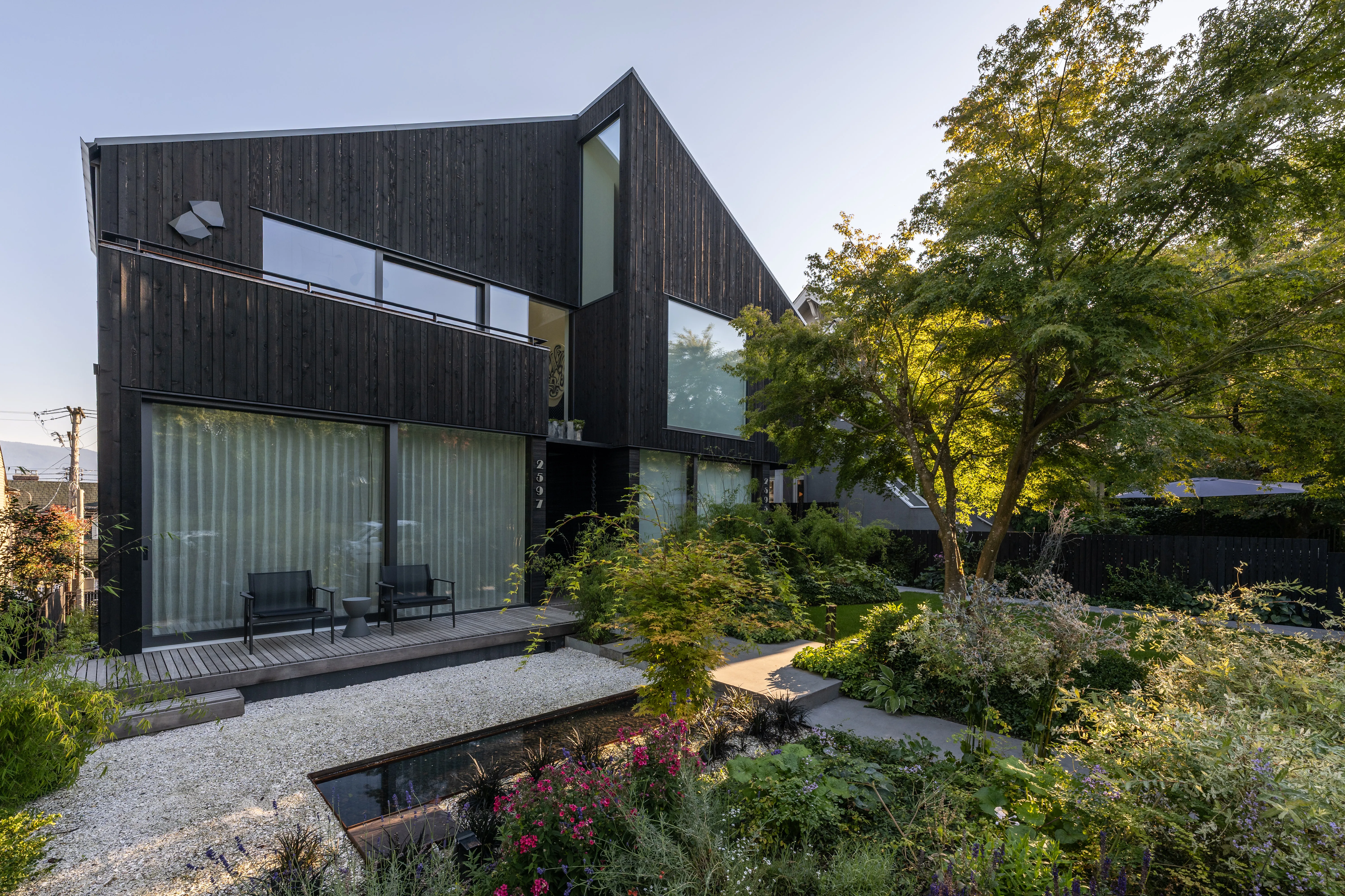 Garden with gravel, water feature and planting at a dark-clad house at West 1st