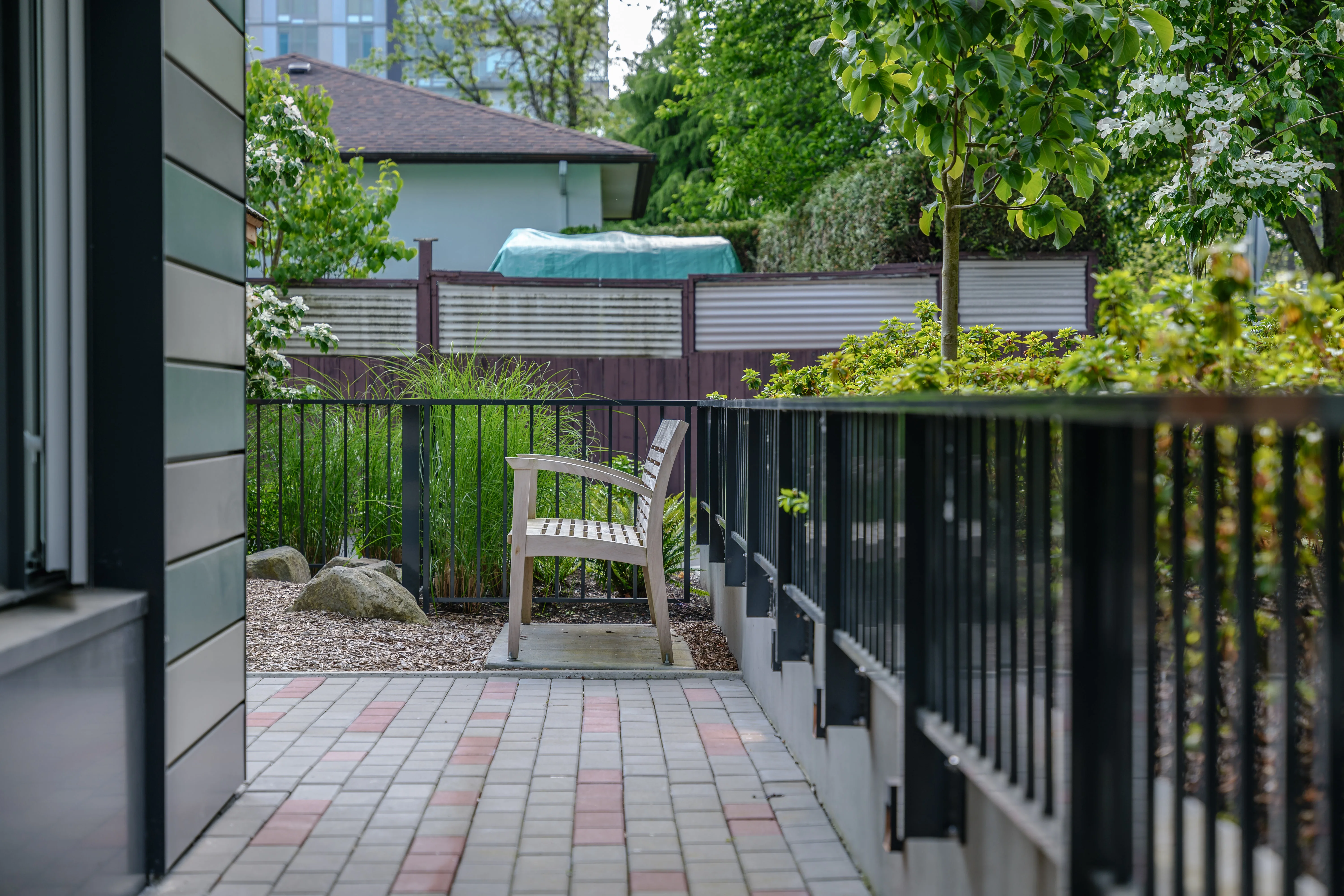 Bench on a brick-paved patio behind a metal fence at Parkhouse