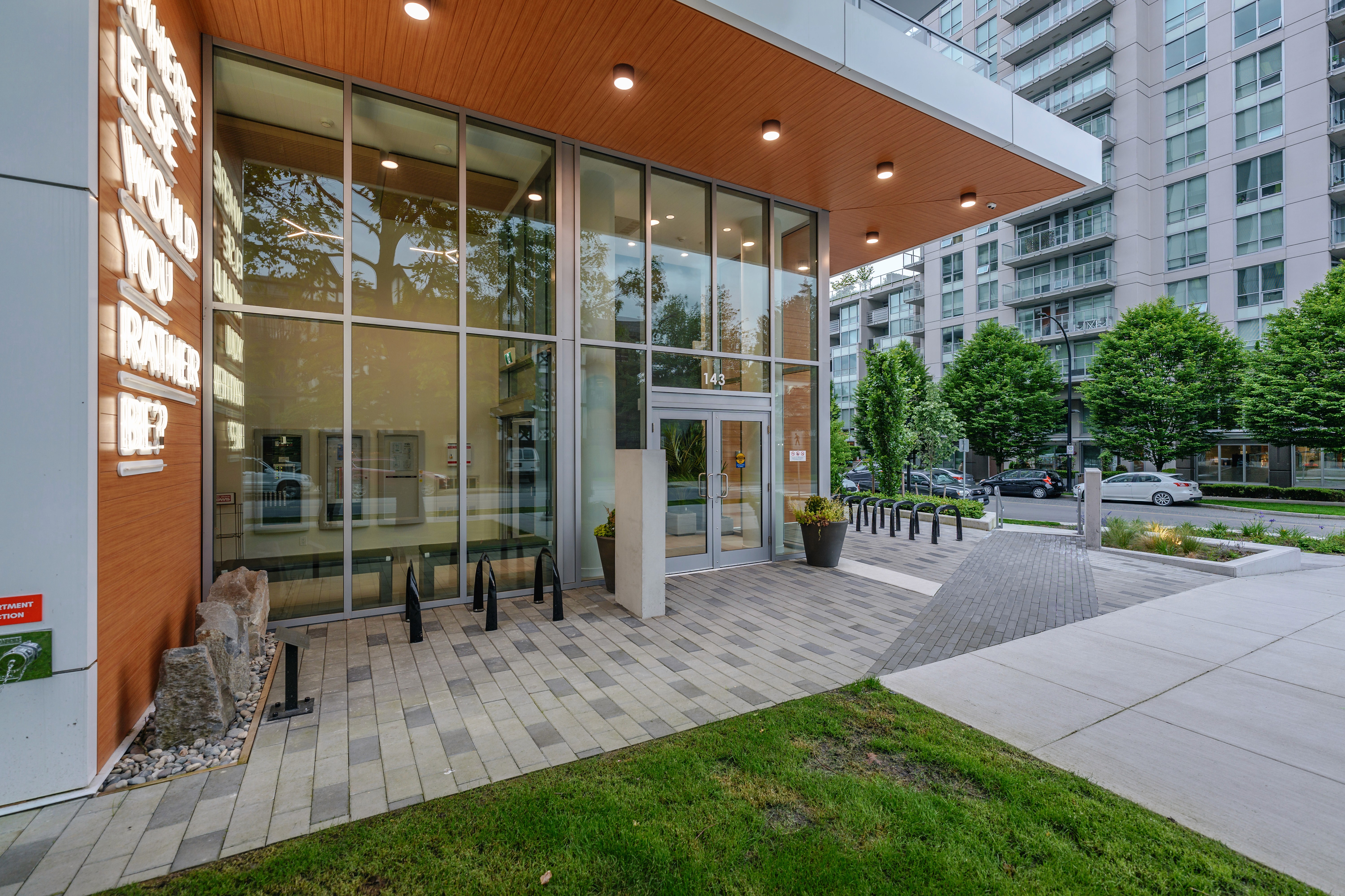 Glass entrance with paved plaza and lawn at Origin