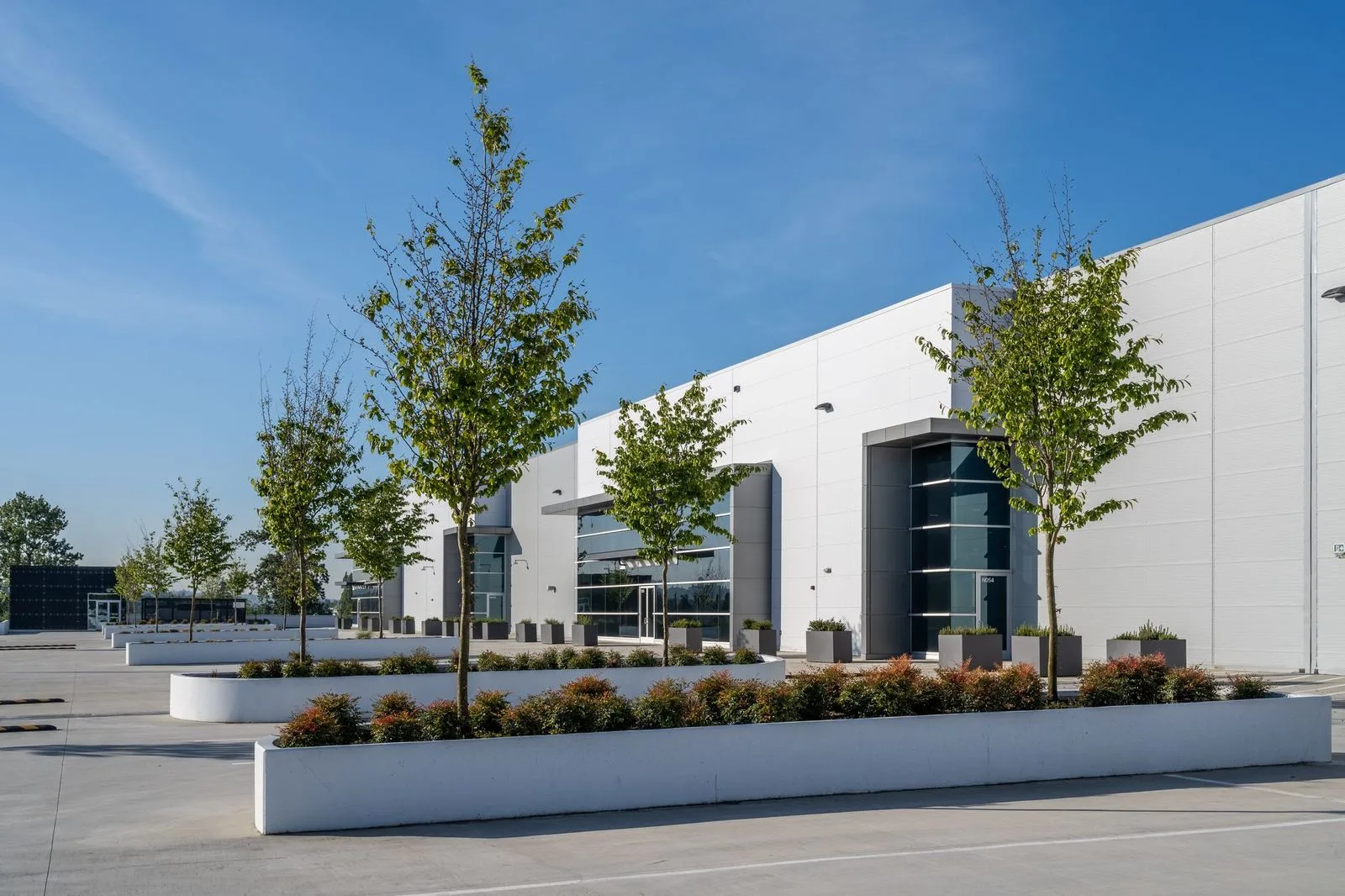 Raised planters with trees along a warehouse frontage at Riverbend Amazon Warehouse