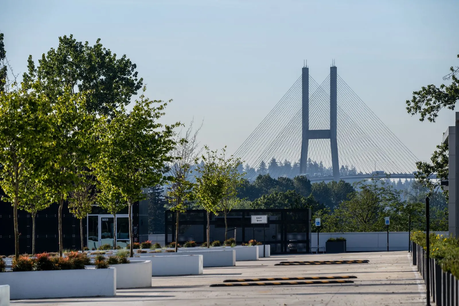 Plaza planters and trees with a bridge in the distance at Riverbend Amazon Warehouse