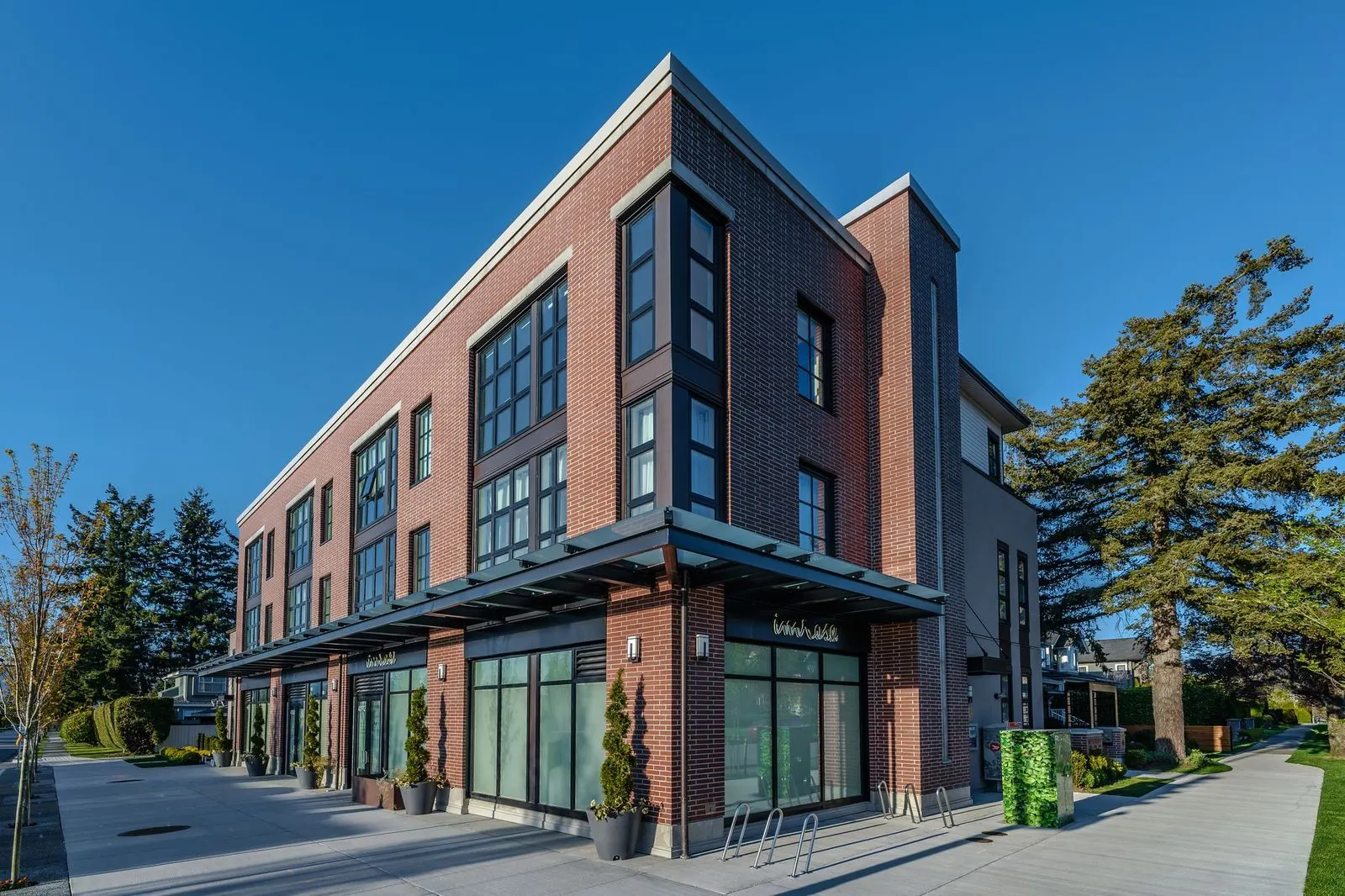 Street frontage of a brick townhome building with planting at Westbury Townhomes