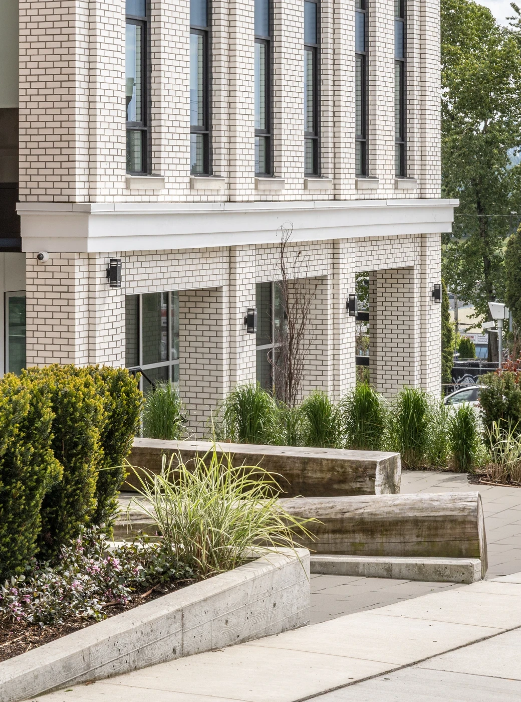 Concrete steps and planted beds at the base of a white brick building