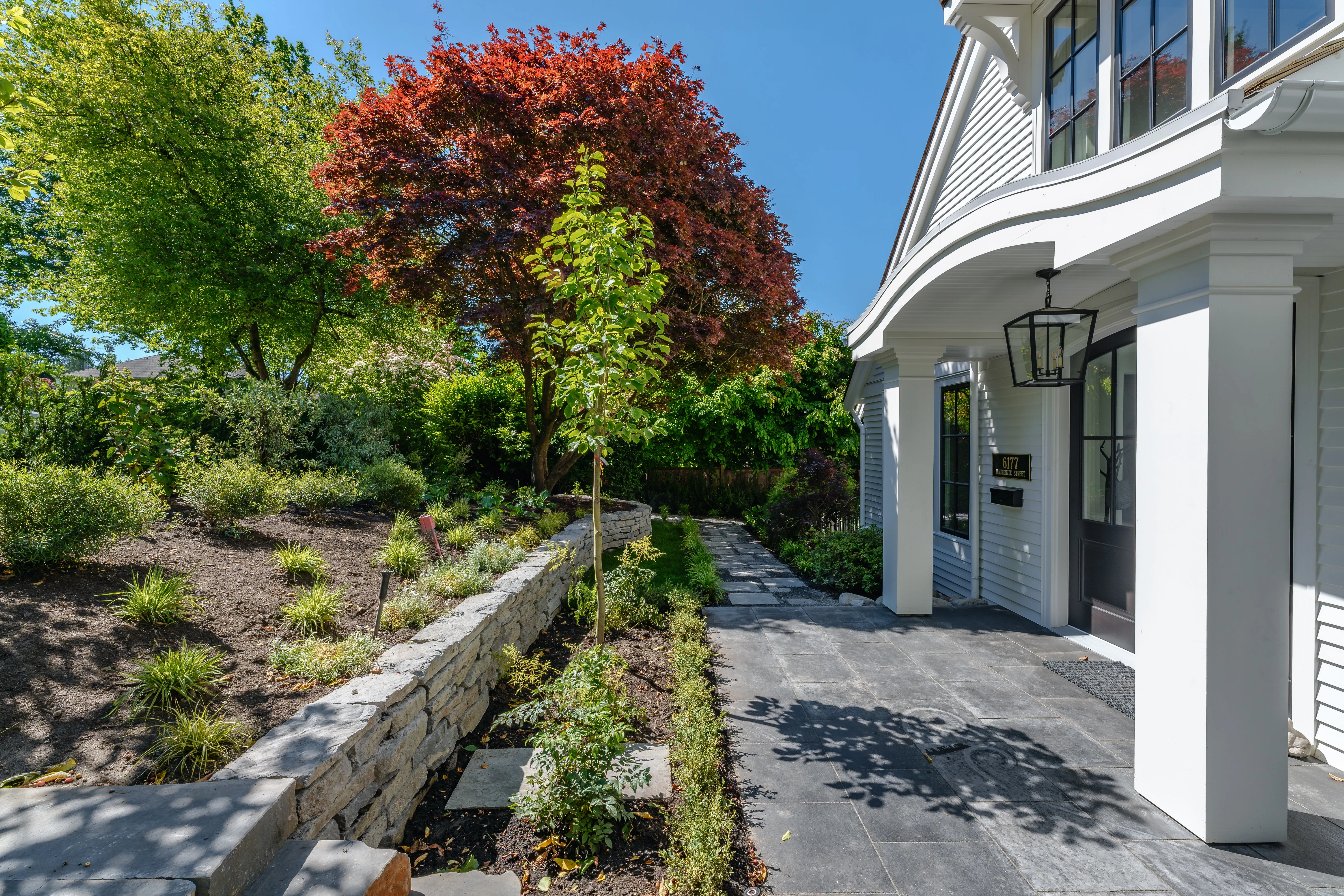 Stone retaining wall and planting beside a paved side path at MacKenzie