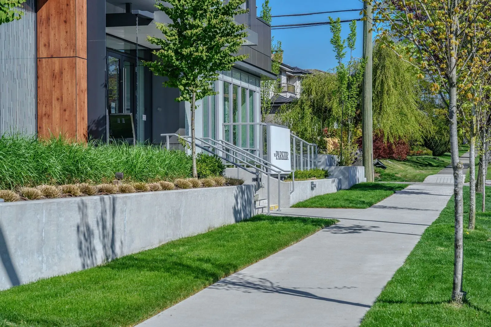 Raised concrete planter, lawn and sidewalk at a building entry at The Parker
