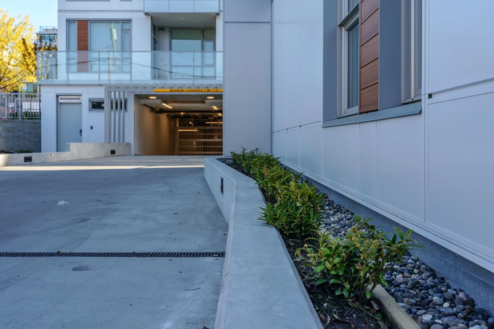 Driveway ramp edged with river rock and planting at Marquise