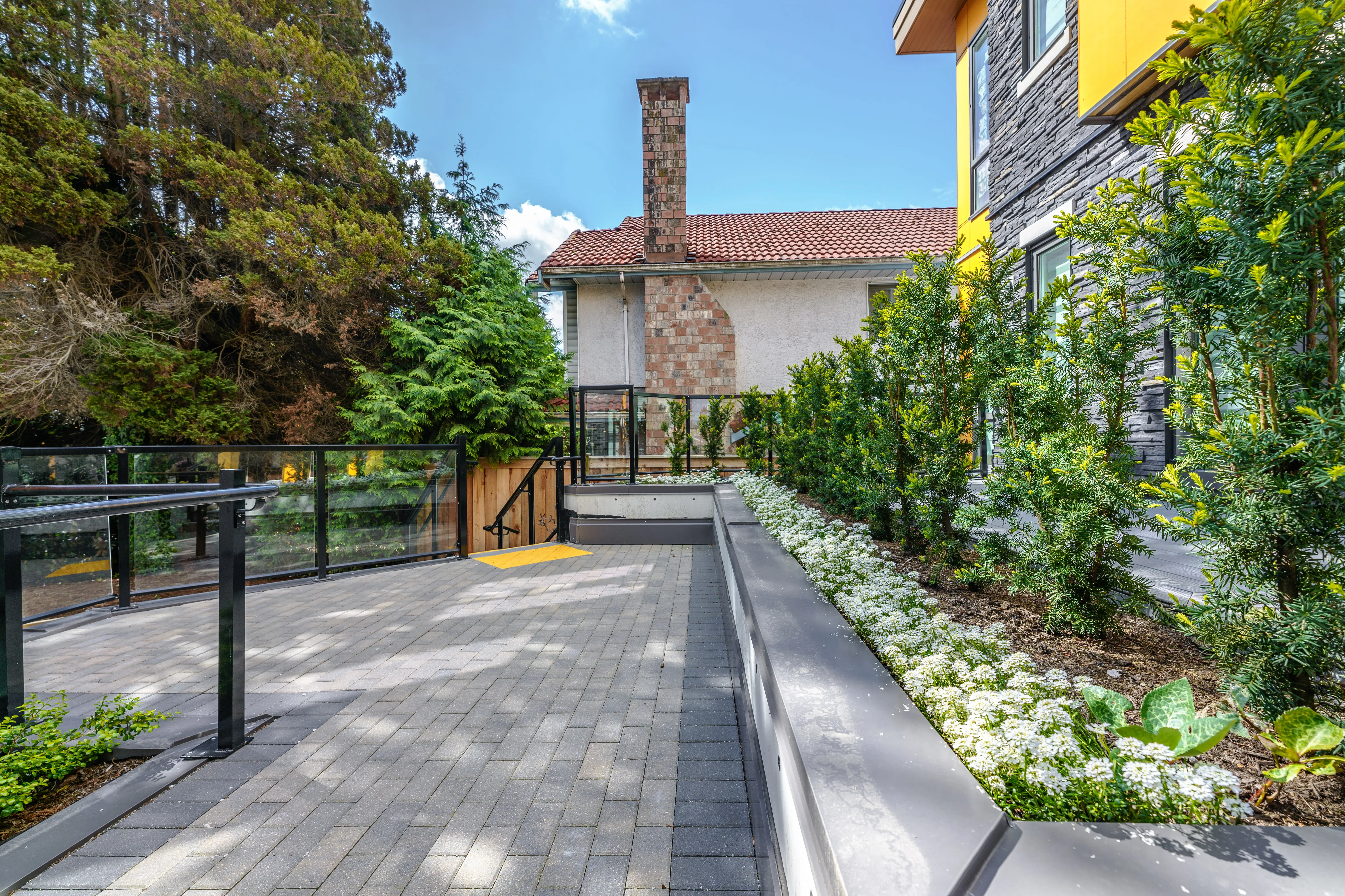 Paved walkway with white flowering planting beside a planter wall at Terraces at Oak Park