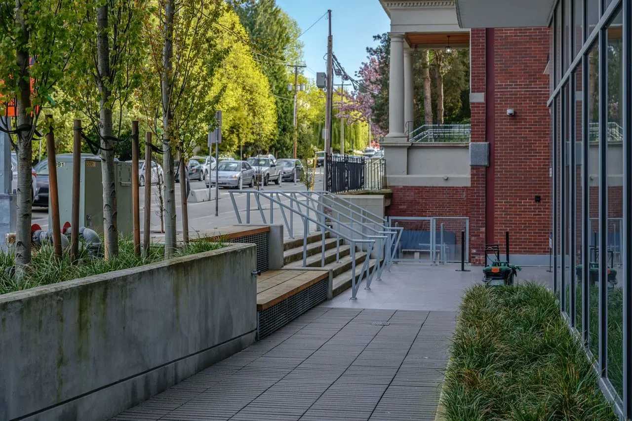 Ramp and stairs with planters beside a brick building at The Beverley