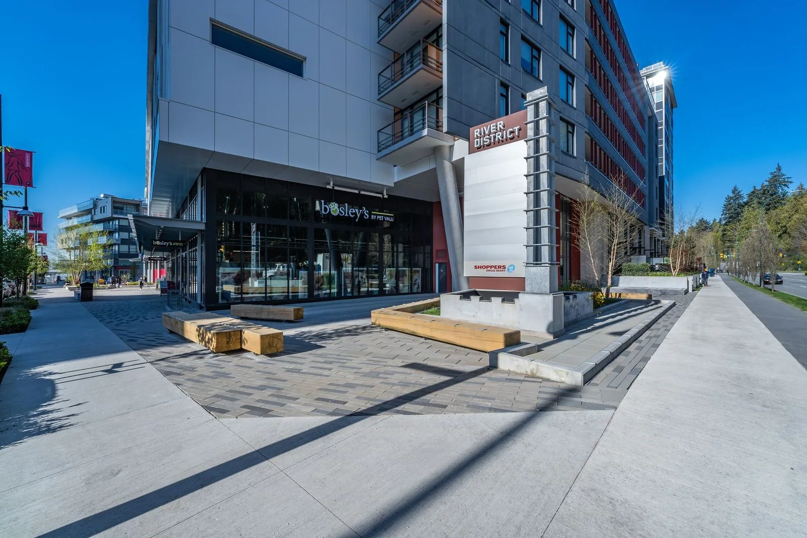 Plaza with timber benches and planting at a building corner at Quartet