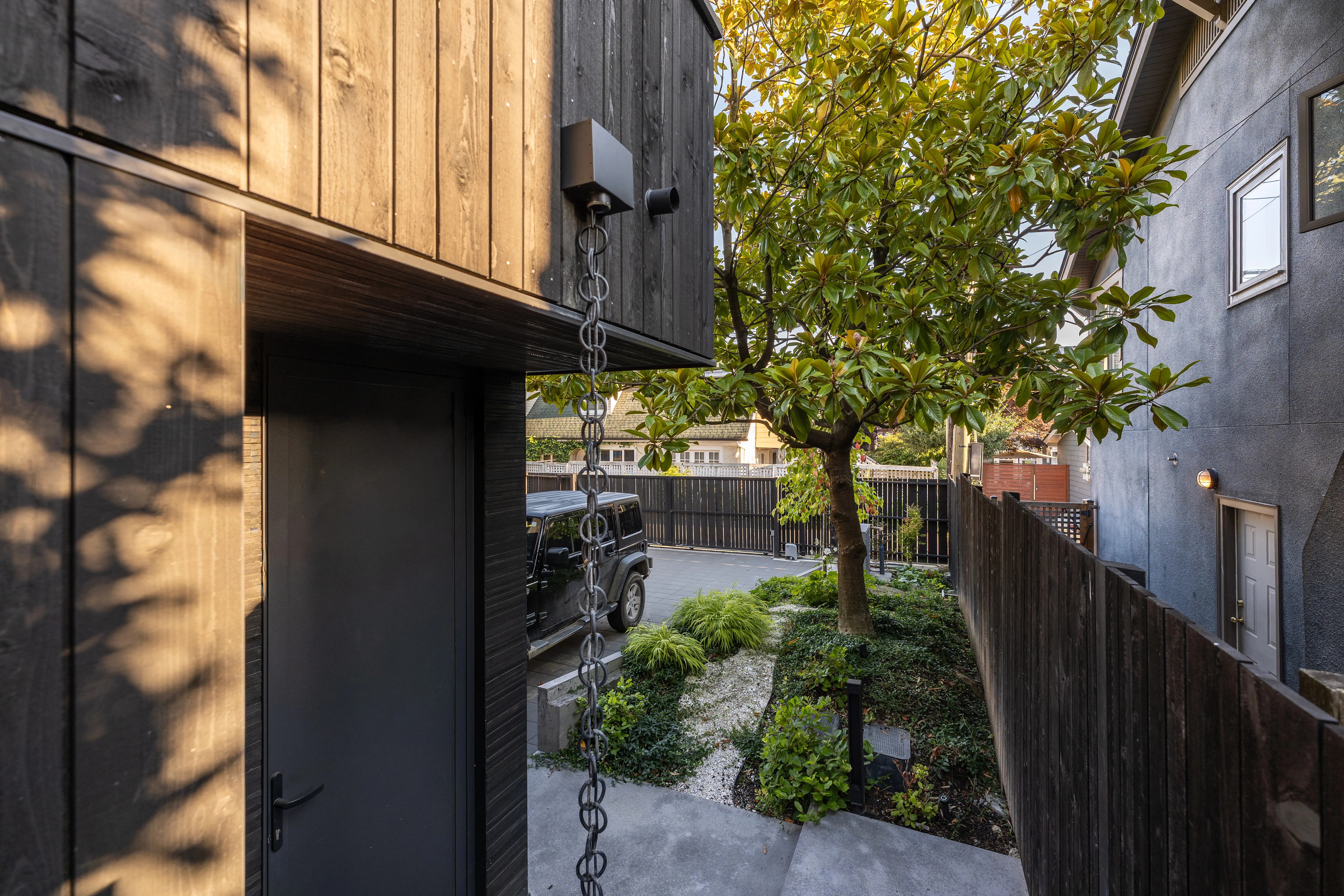 Side entry path with planting beside a timber-clad house at West 1st