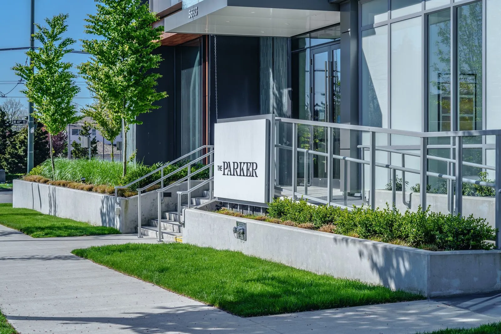 Entrance sign, lawn and planters at the building entry at The Parker