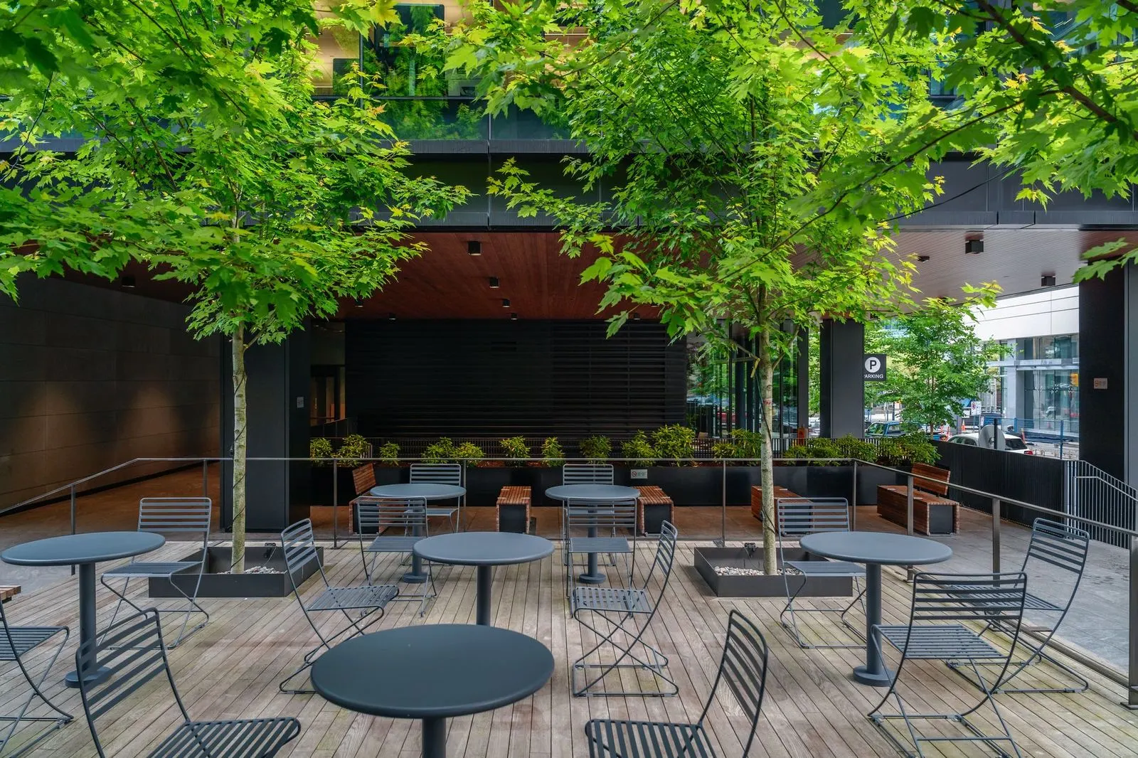 Tables and chairs under trees on a timber deck at Amazon Downtown