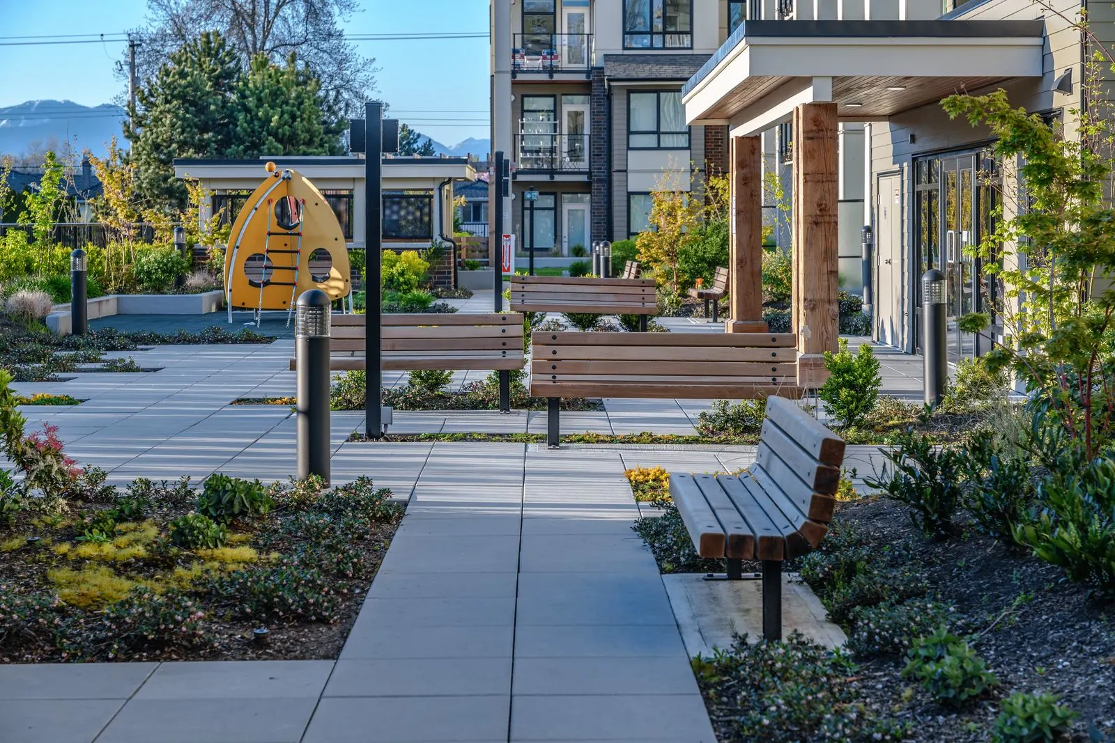 Courtyard walkway with benches, planting and a play feature at Spark
