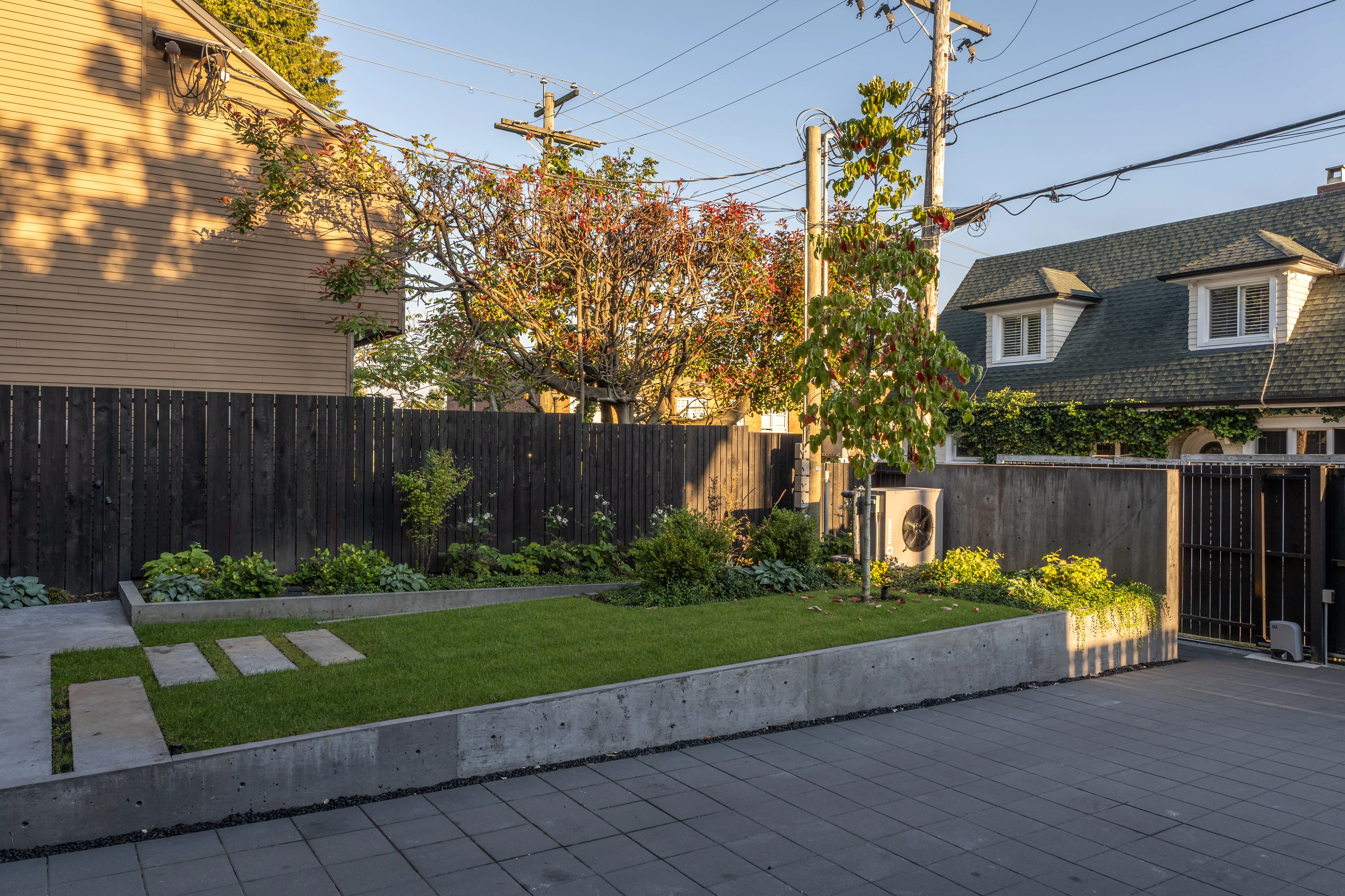 Lawn and paved patio behind a dark timber fence at West 1st