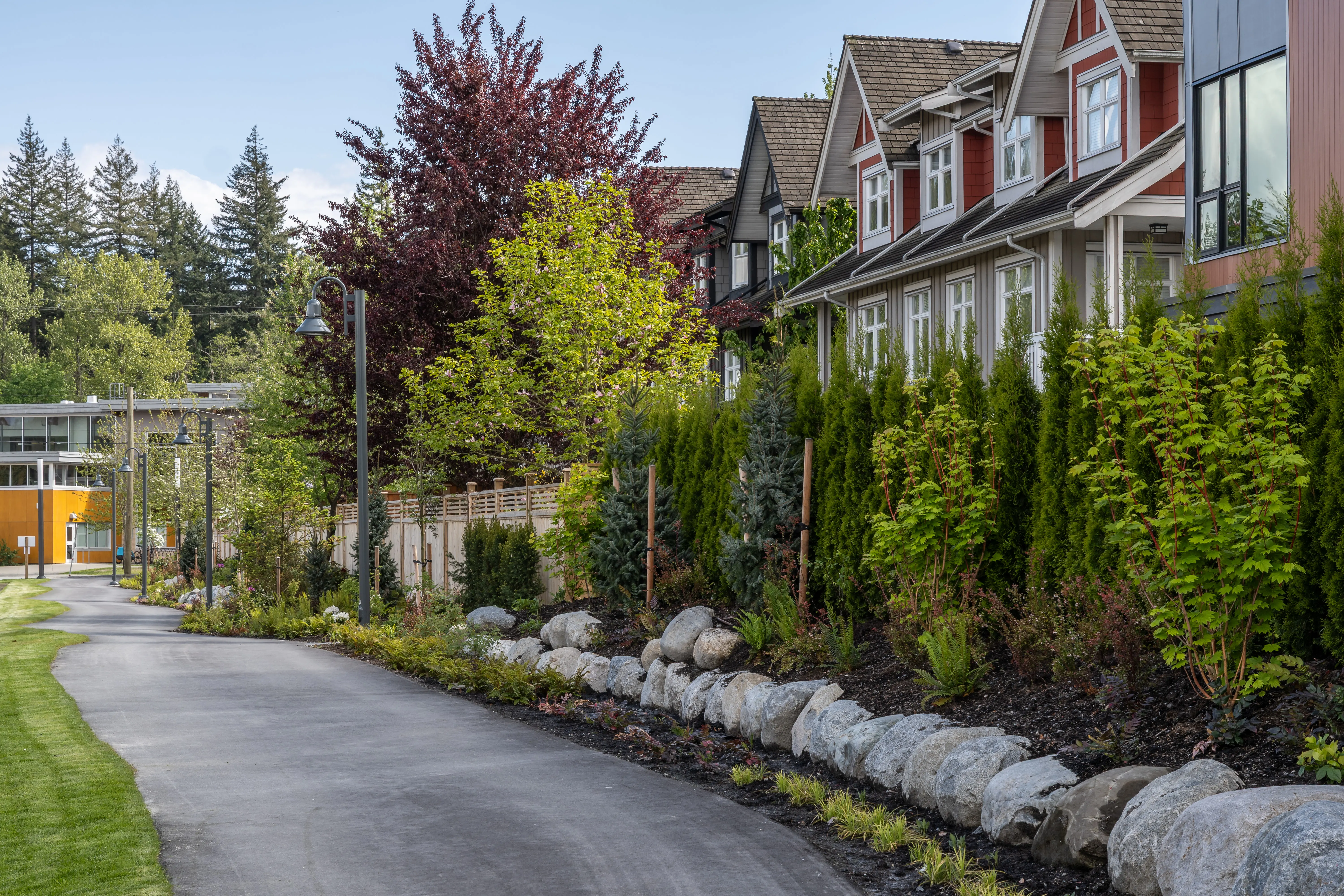 Curving paved trail with boulders and shrub planting at Community Green and Ortona Trail