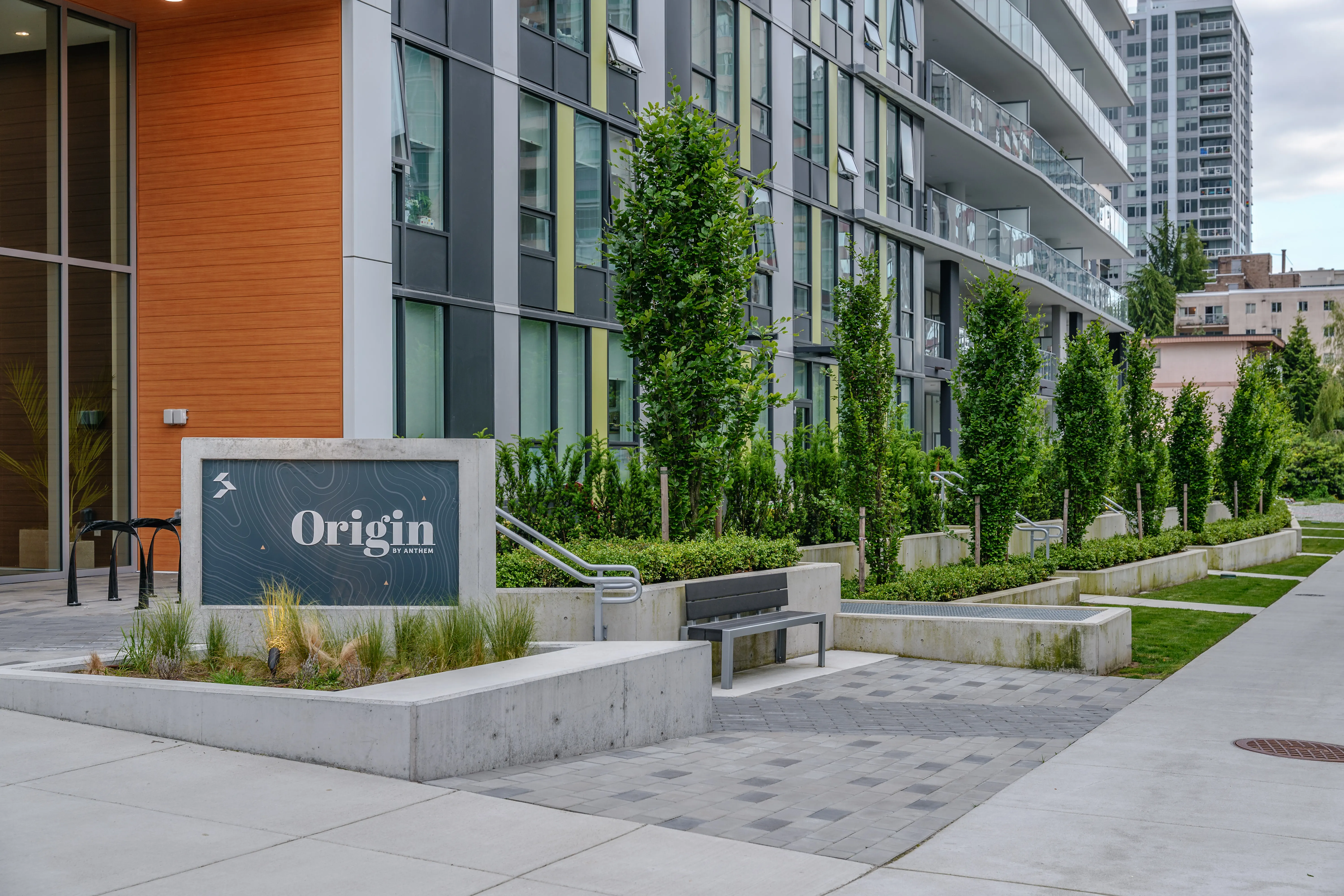 Origin building sign with planting and columnar trees