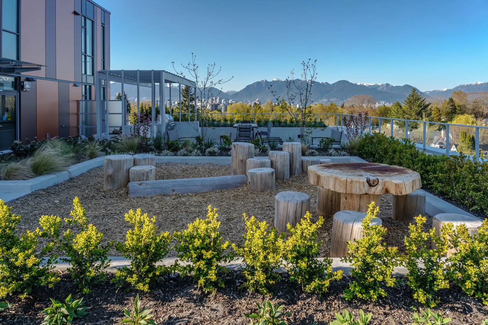 Rooftop play area with timber log seats and planting at Marquise