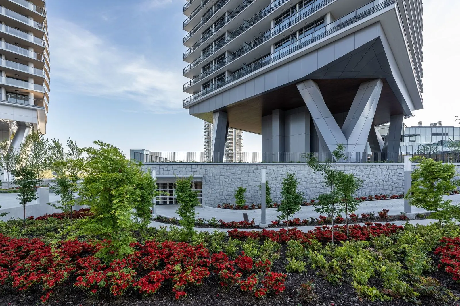 Red flowering planting beds in front of a tower podium at Brentwood 1A