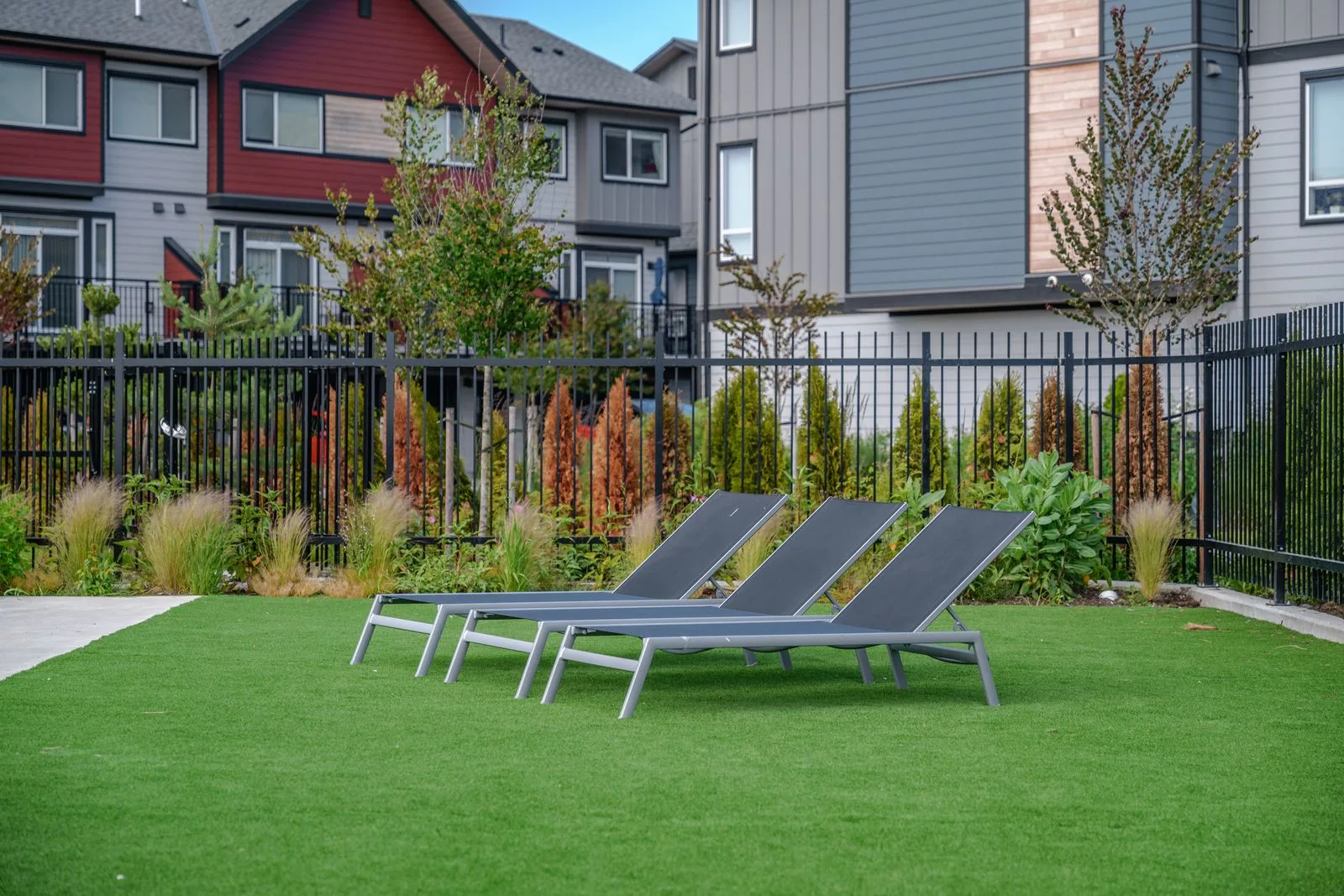 Lawn with lounge chairs and planting along a fence at Boardwalk