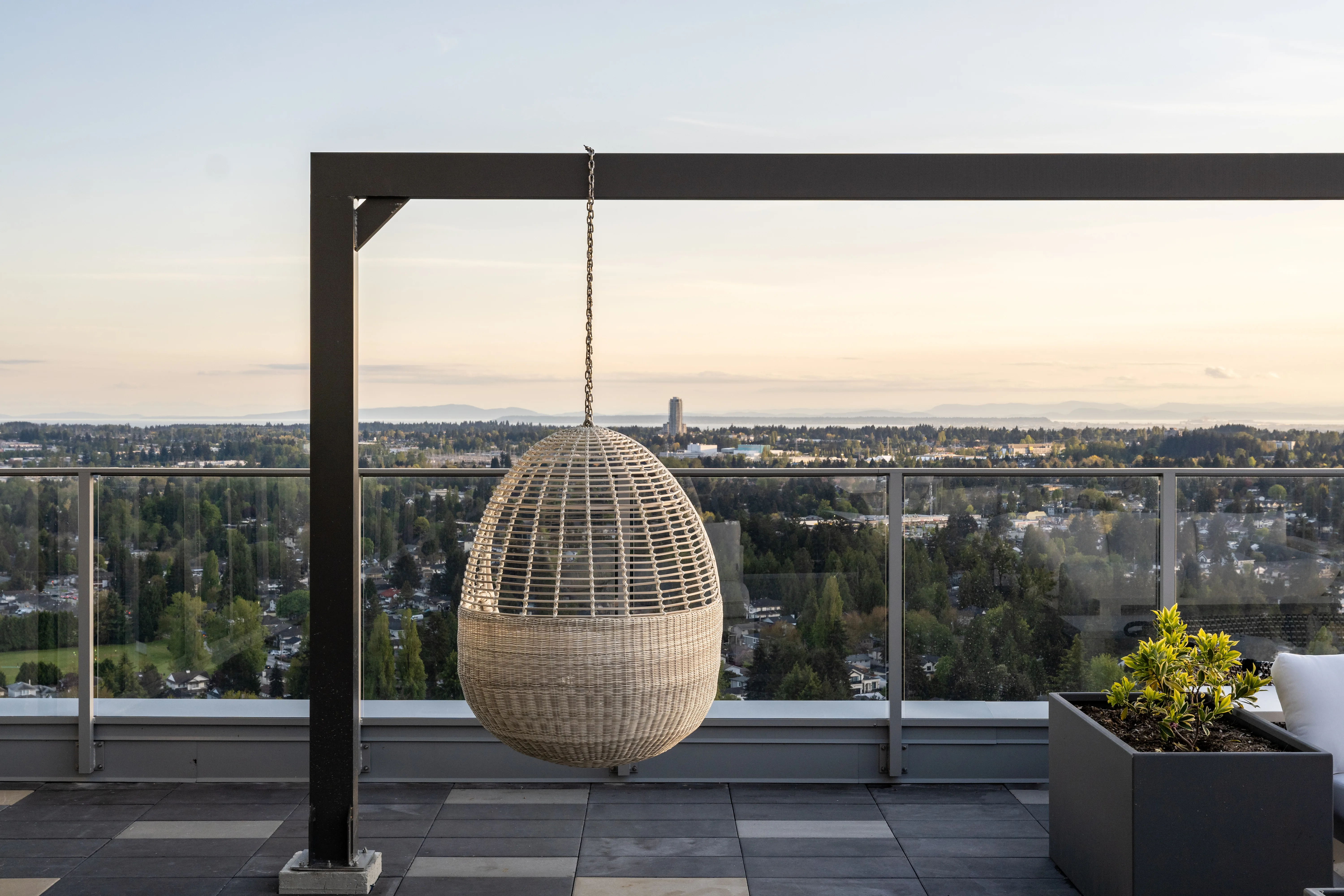 Hanging egg chair on a rooftop terrace with city views at The Holland II
