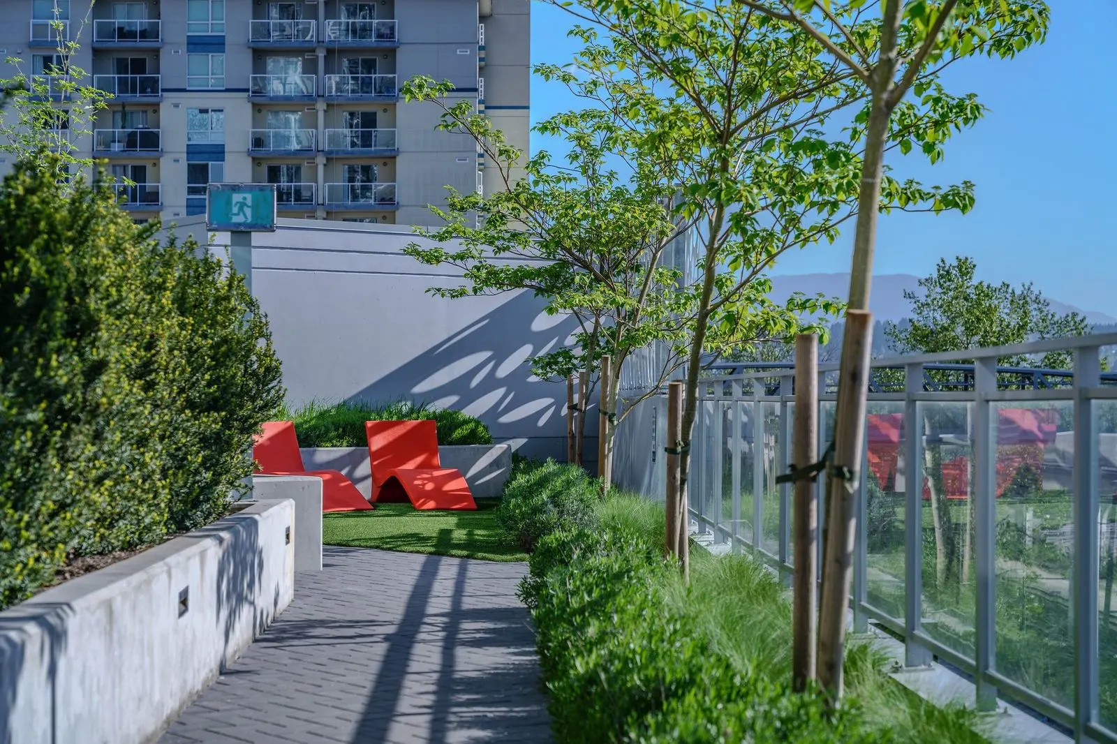 Rooftop path with planting and red lounge chairs at Brewery District 6