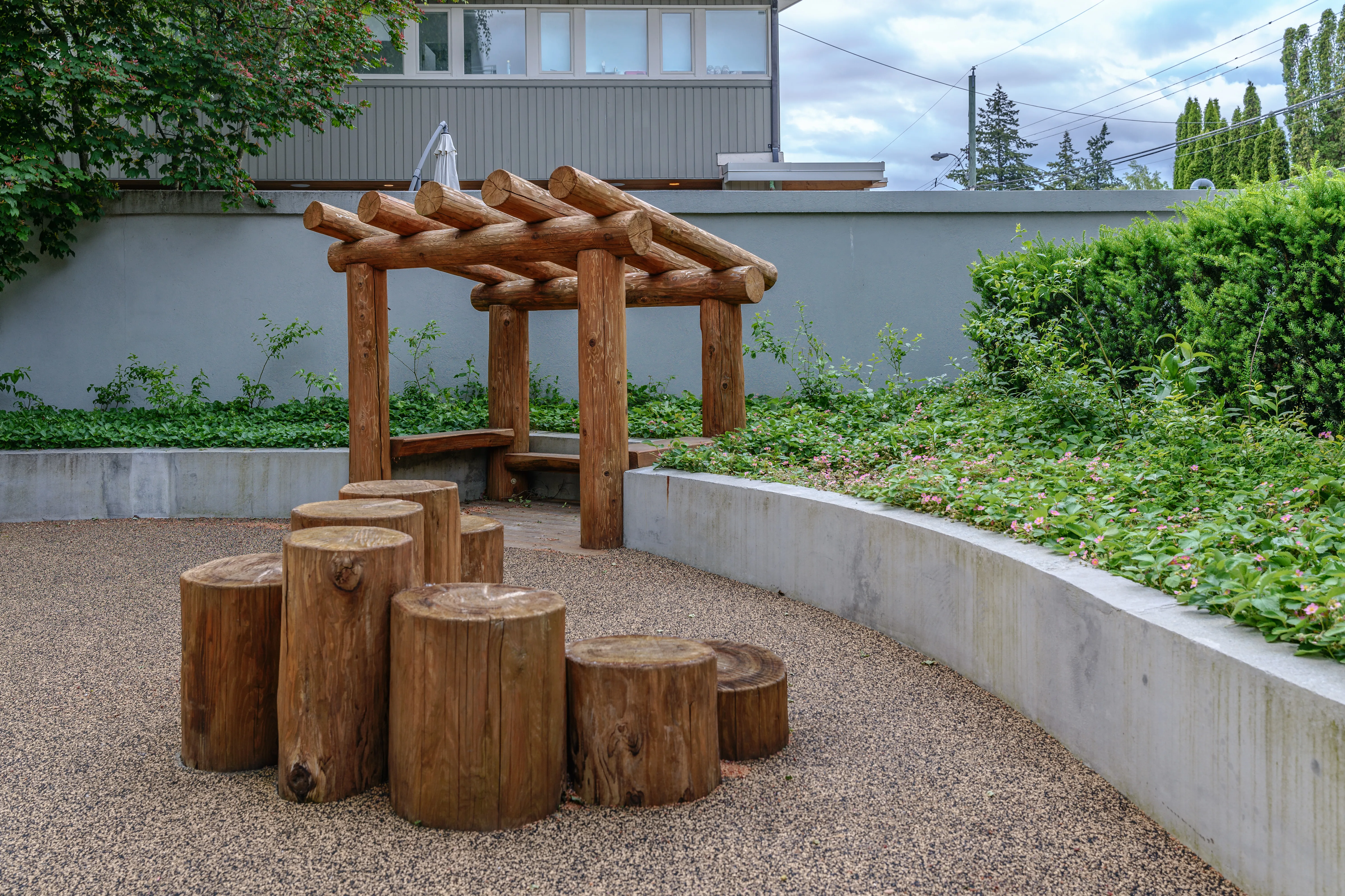 Timber log seats under a small timber shelter in a play area at Basalt