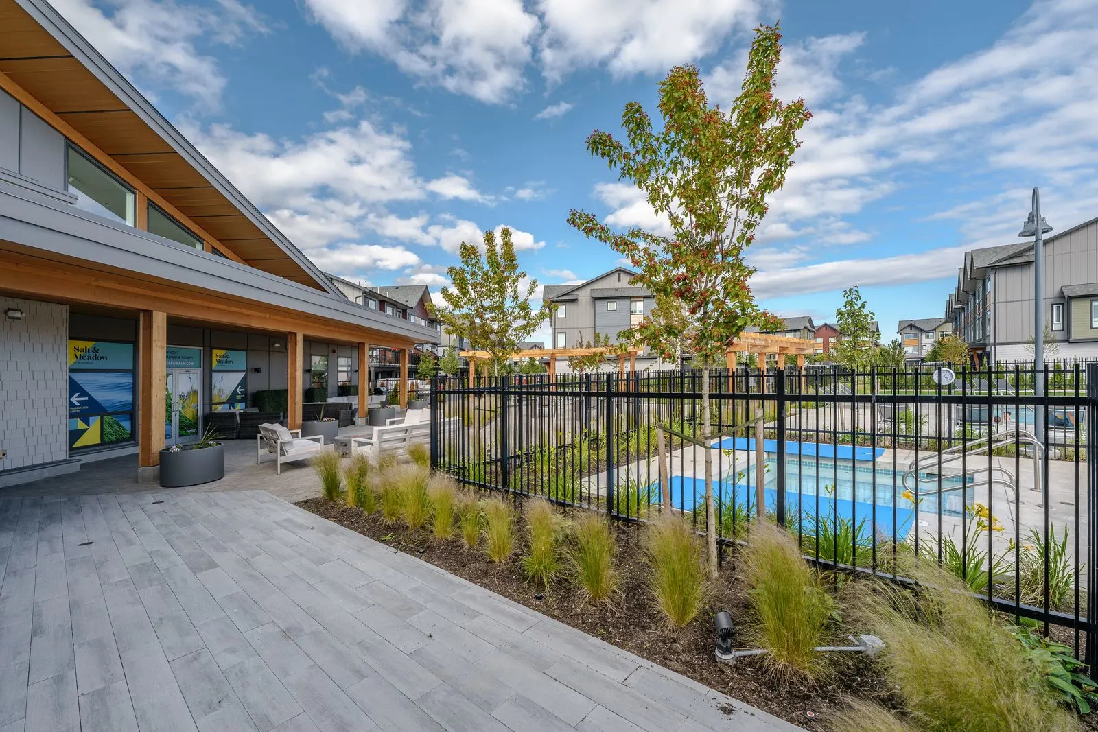 Pool deck with ornamental grasses along a fence at Boardwalk