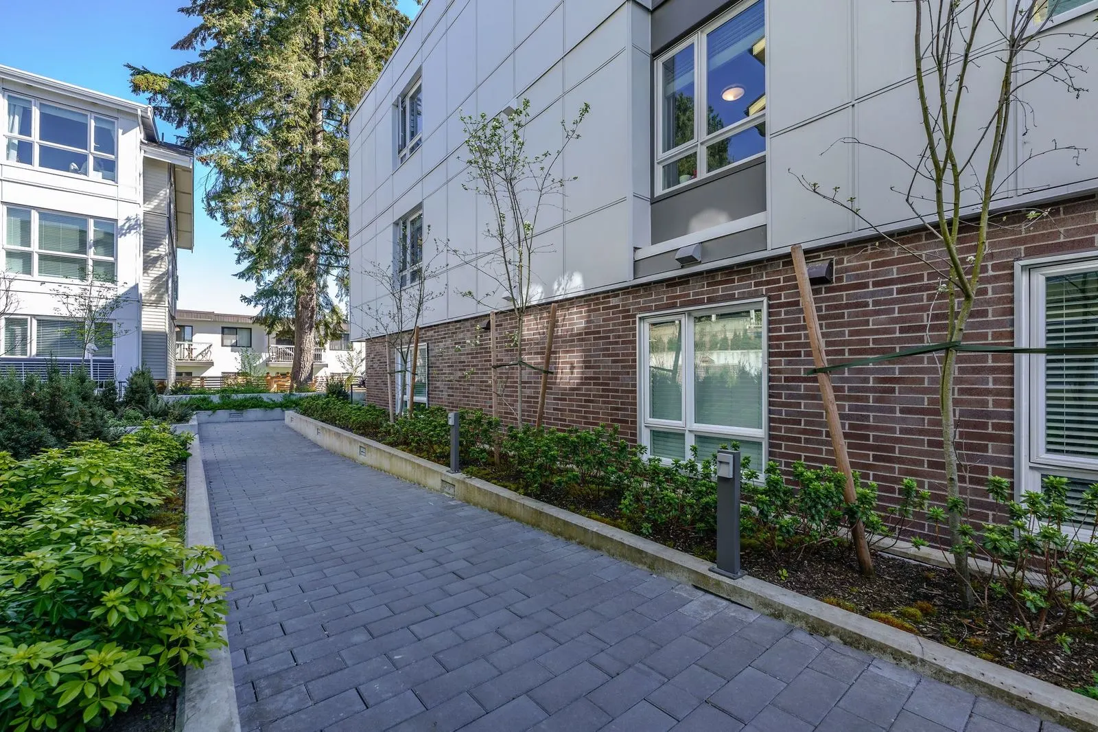 Paver walkway beside a brick residential building at Conrad