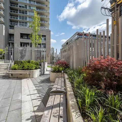 Planted walkway with timber benches and vertical posts between towers