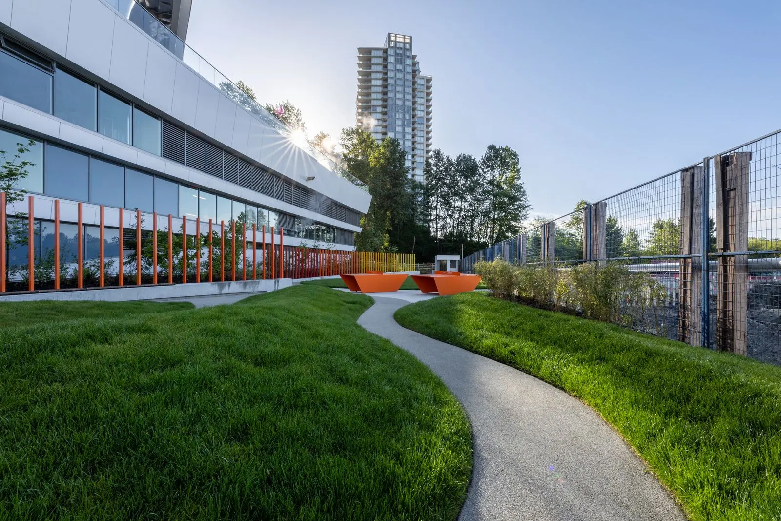 Curved path through lawn with orange seating beyond at Brentwood 1B