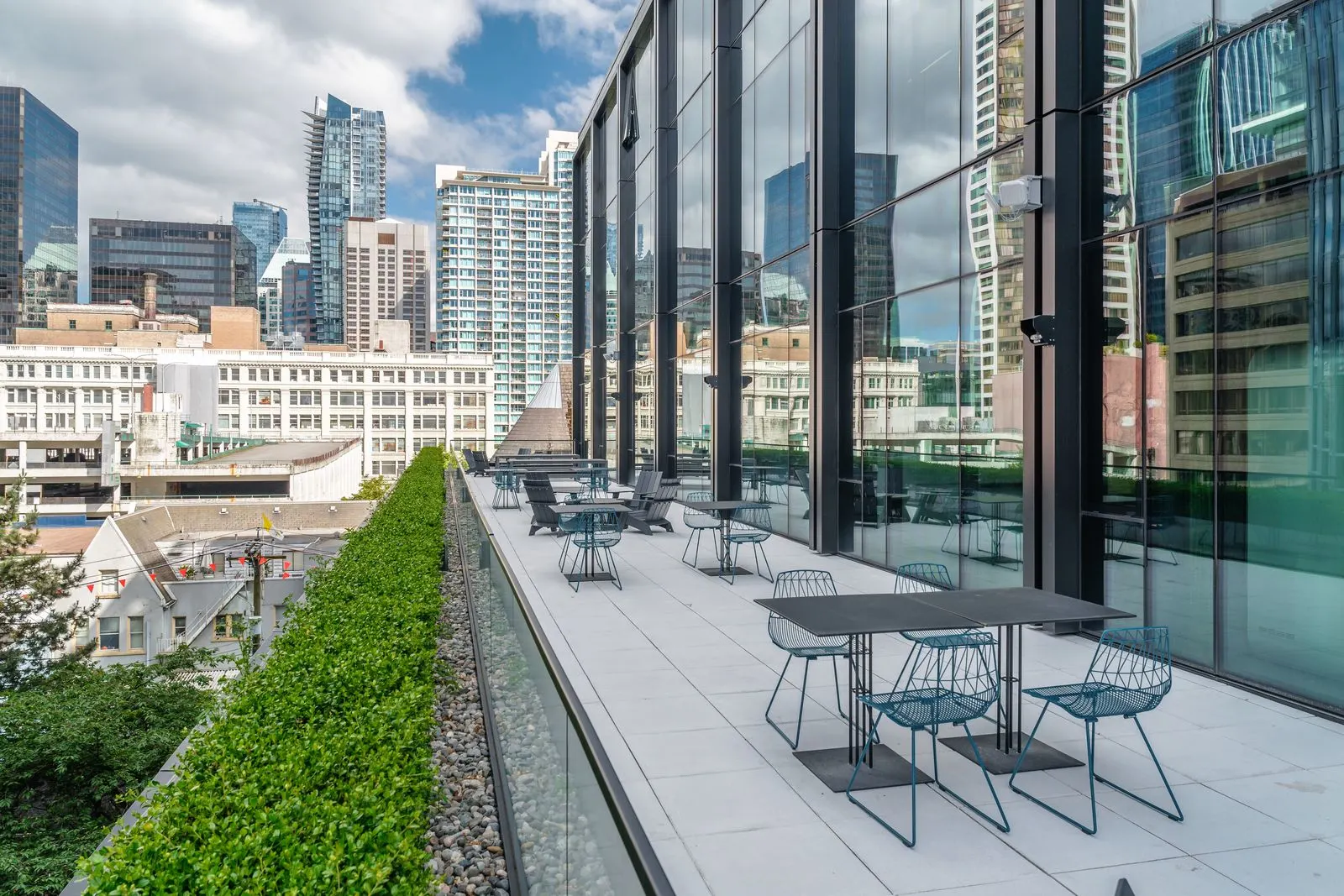 Rooftop terrace with tables beside a planted edge at Amazon Downtown