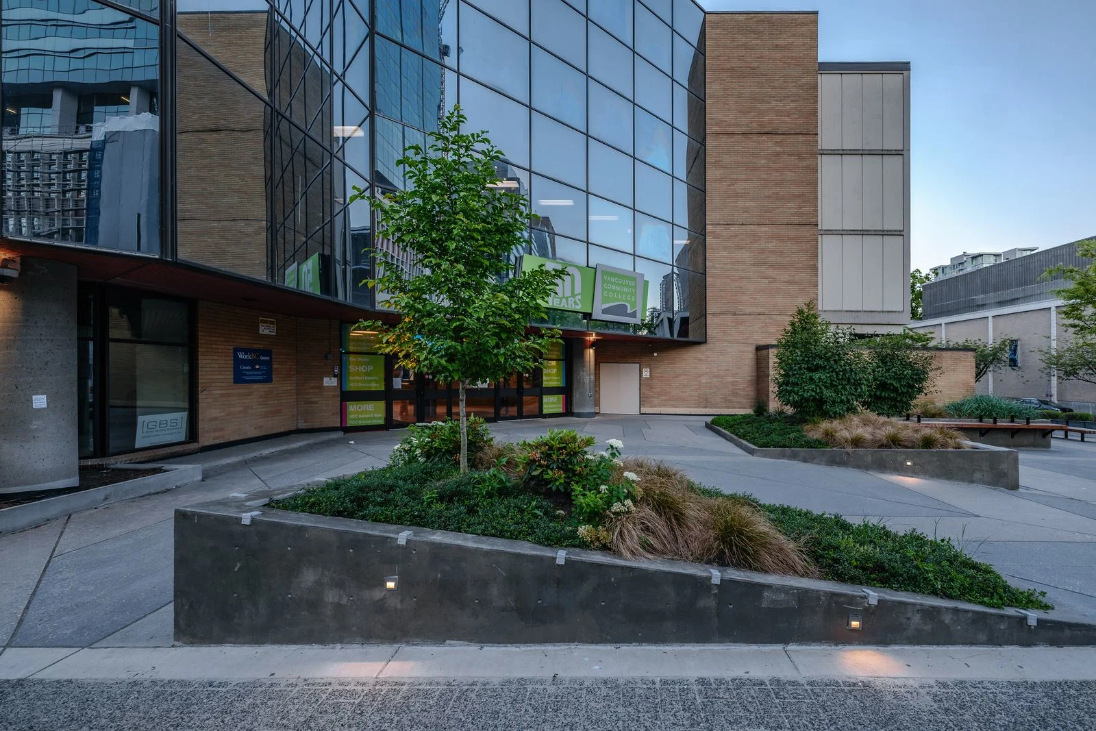 Lit planters and trees at a campus entrance plaza at Vancouver Community College