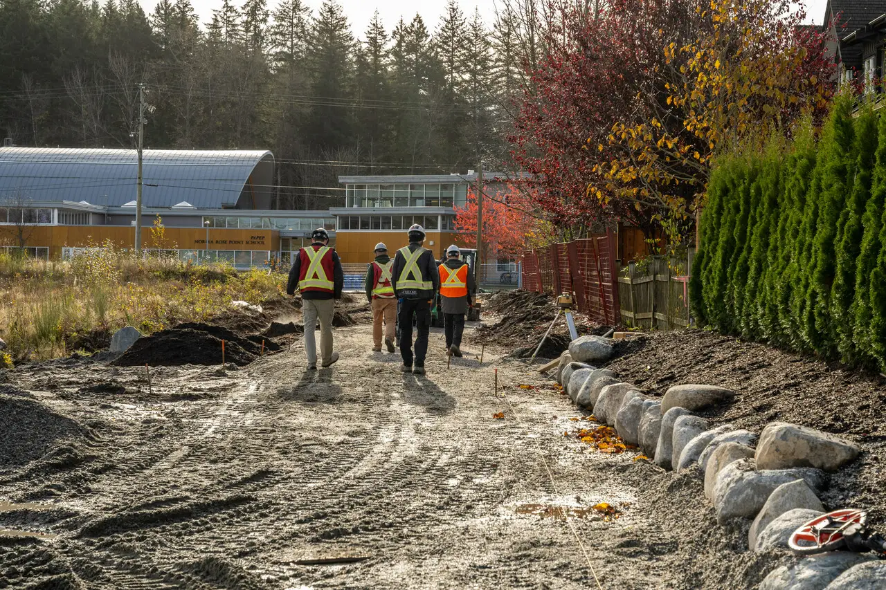 Crew in safety vests walking along a graded site during landscape construction