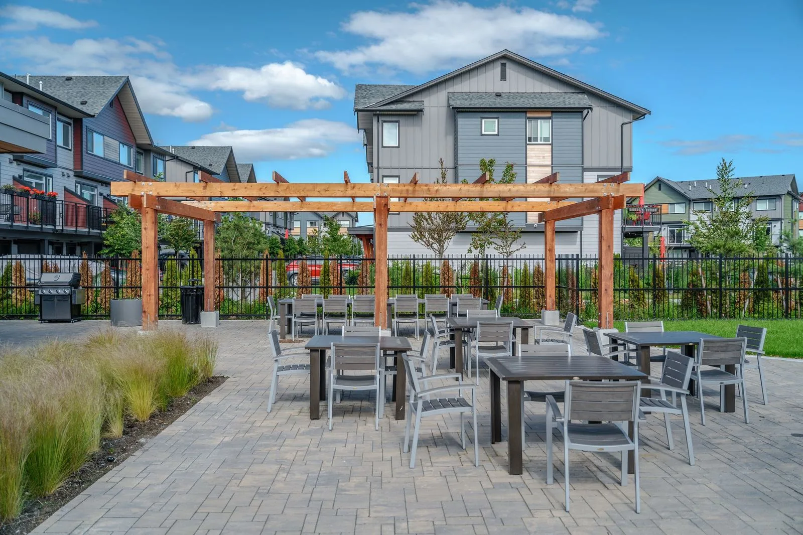 Paver patio with dining tables under a timber pergola at Boardwalk