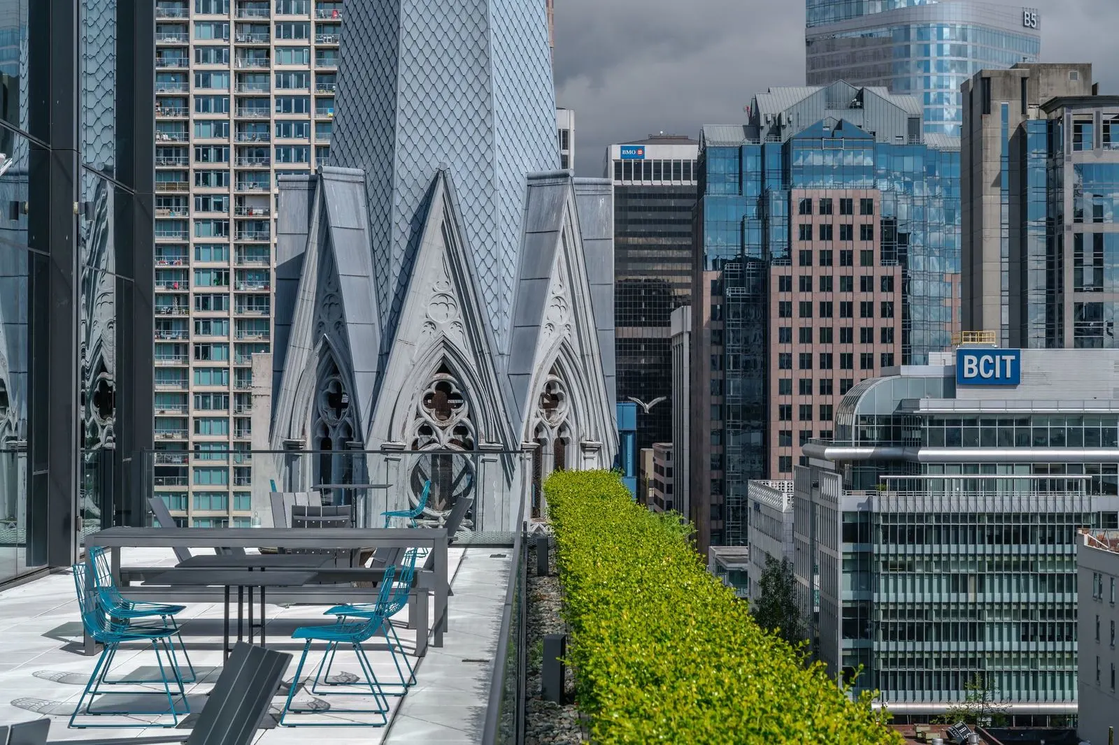 Rooftop seating beside a hedge with a church spire beyond at Amazon Downtown
