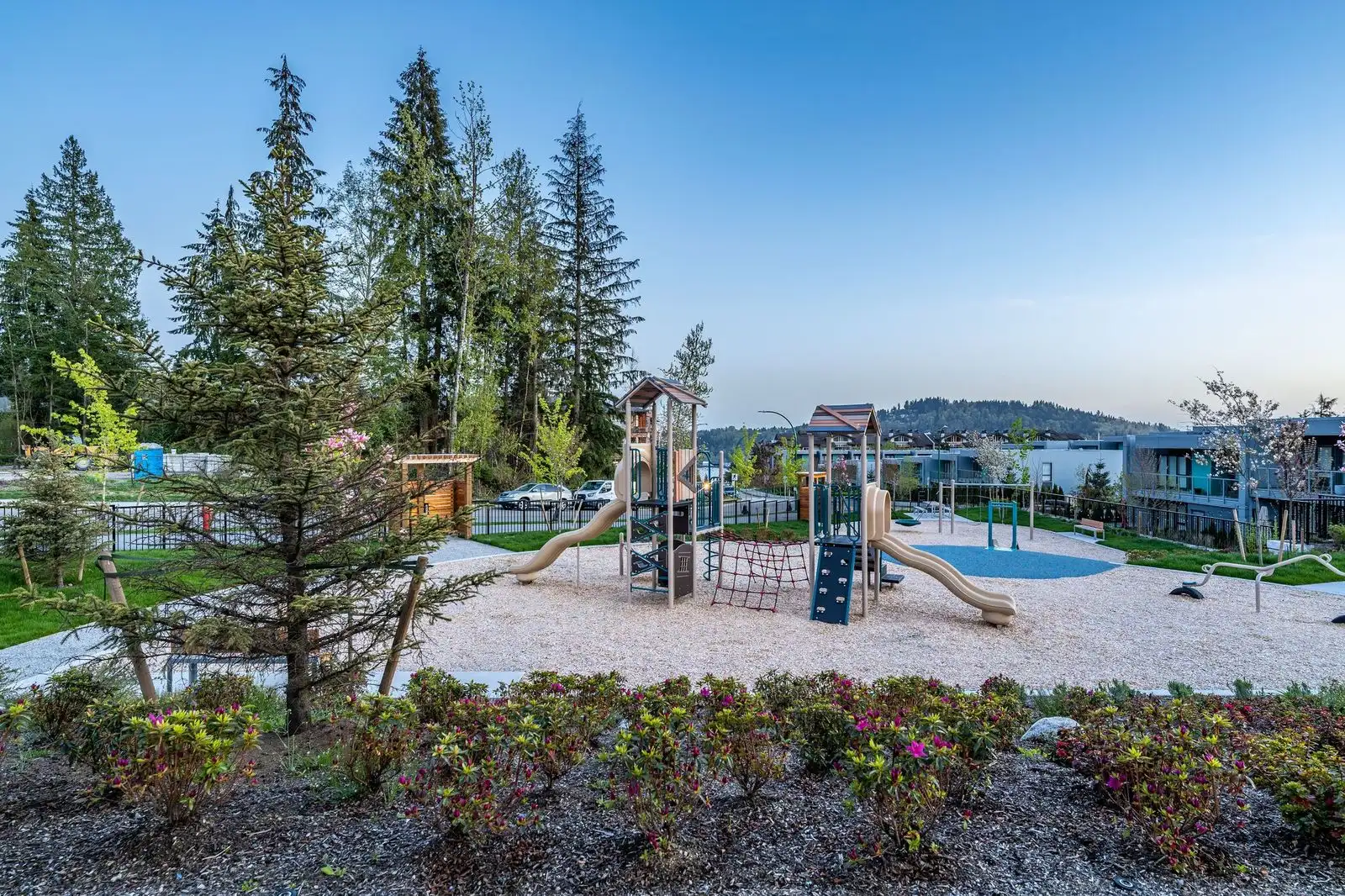 Playground beyond flowering planting and evergreens at Seymour Village Amenity Park