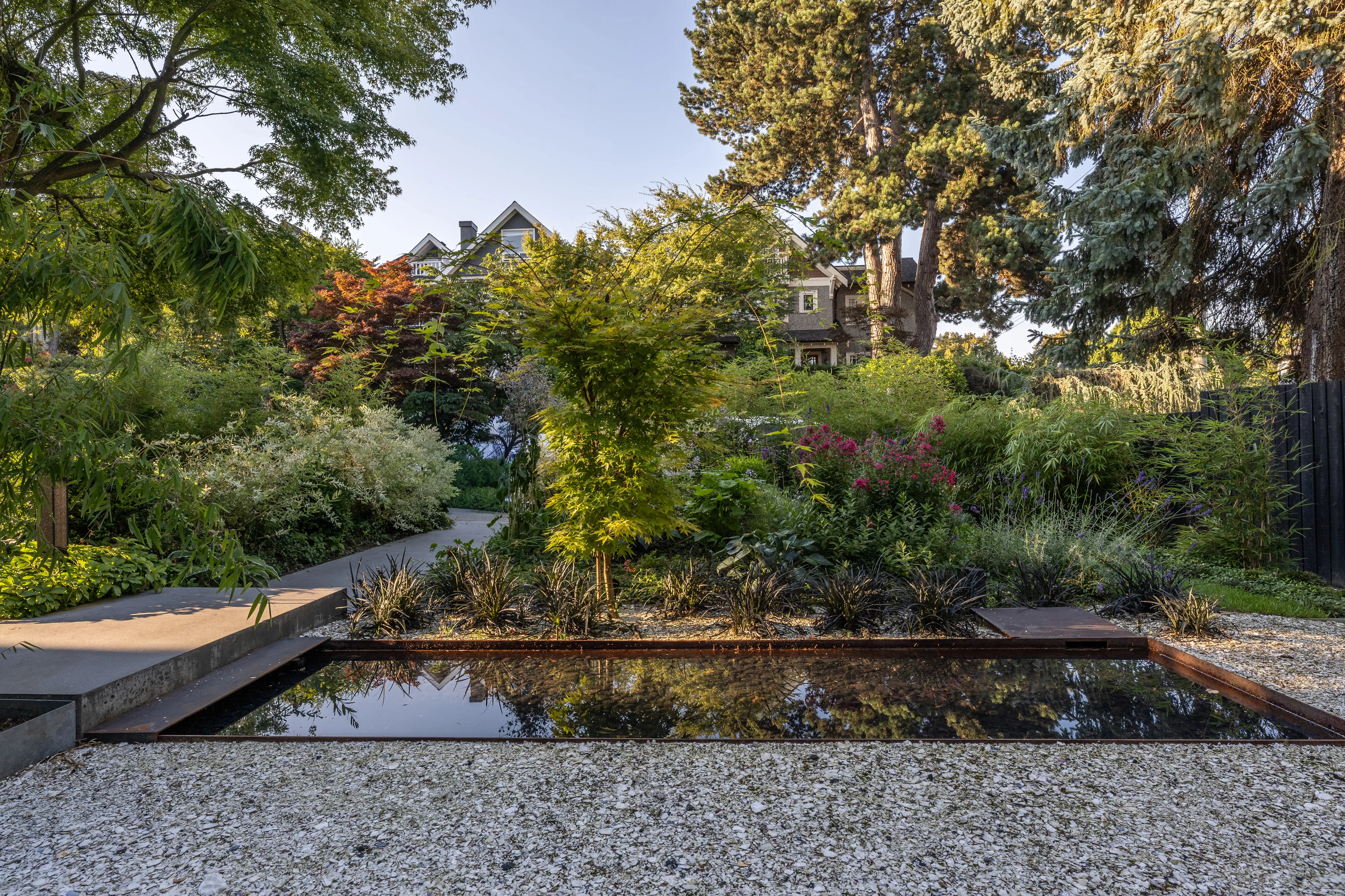 Rectangular water feature in gravel with garden planting at West 1st