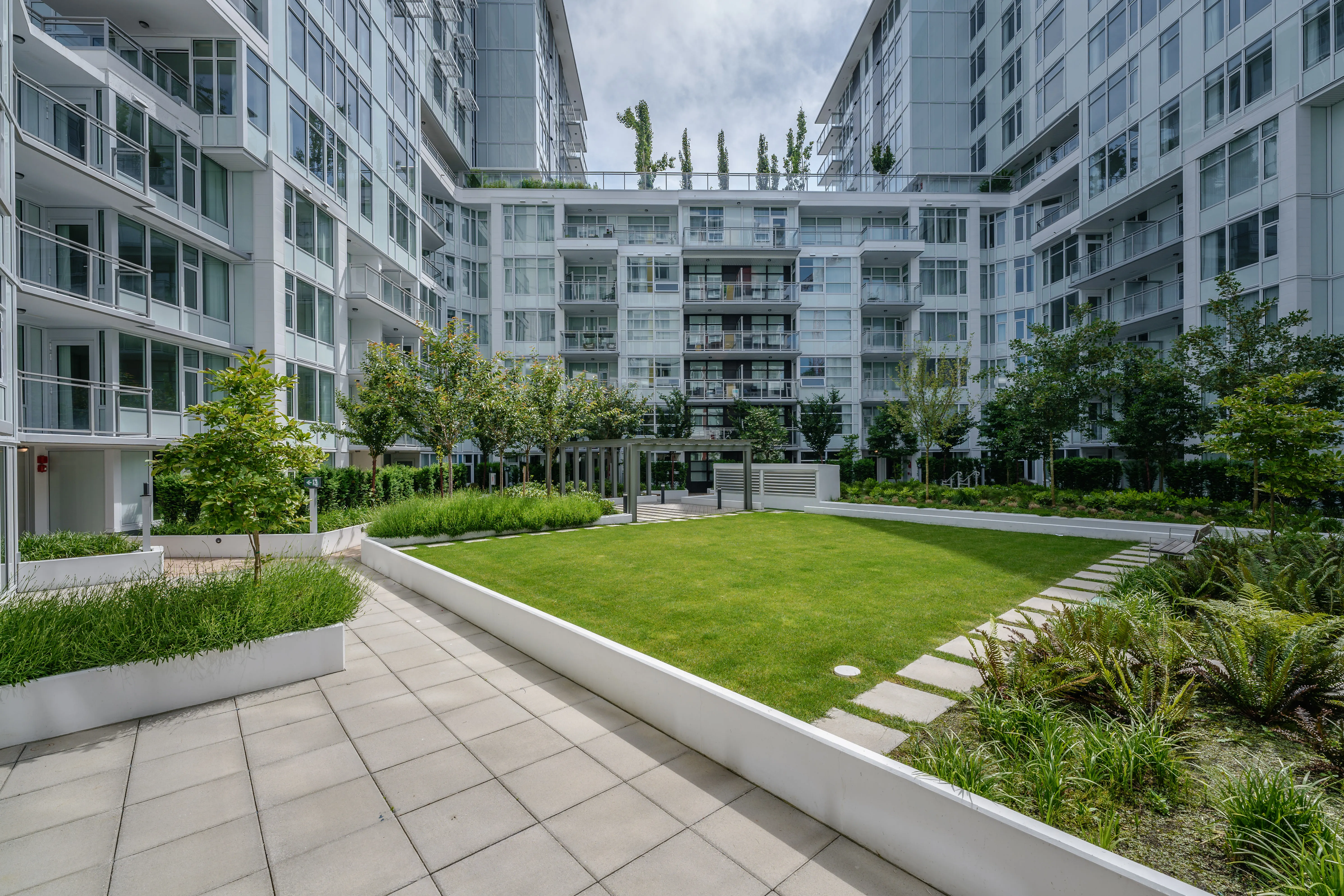 Courtyard lawn bordered by paths and planting between towers at Torino