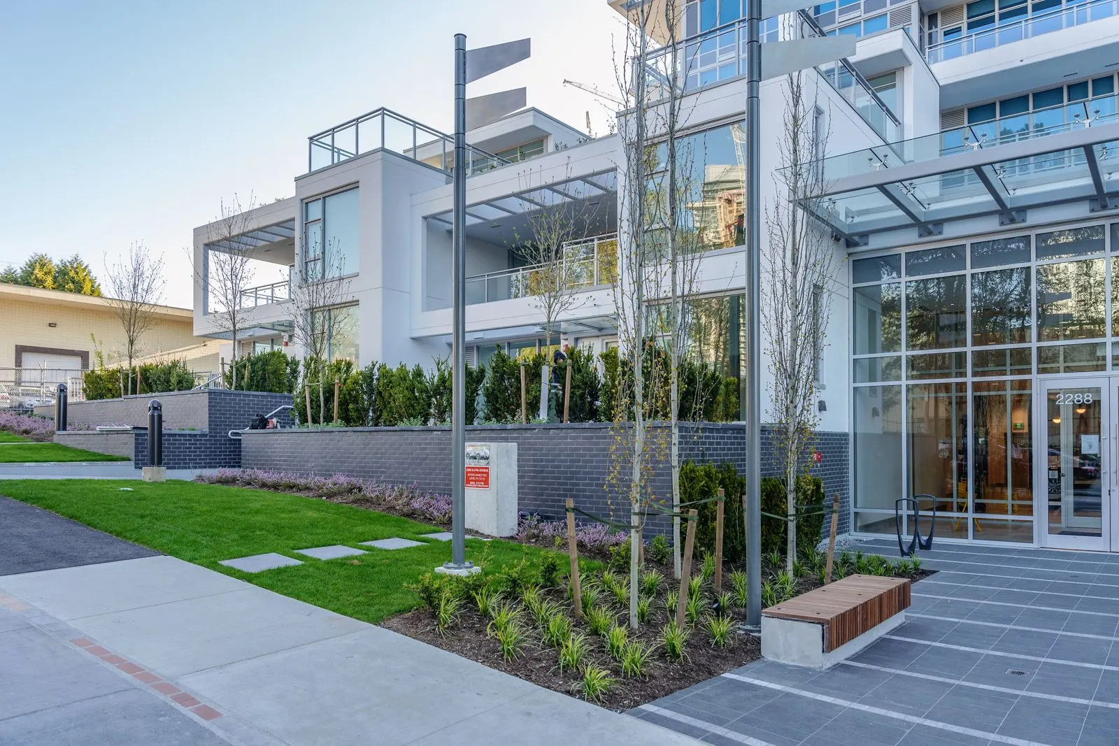 Lawn, planting and benches at a building entrance at Alpha Lumina